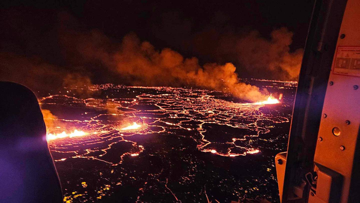 En esta imagen distribuida por el Departamento de Protección Civil y Gestión de Emergencias de Islandia se ven ondas de humo y lava fluyendo que tiñen el cielo de color naranja durante una erupción volcánica en la península de Reykjanes