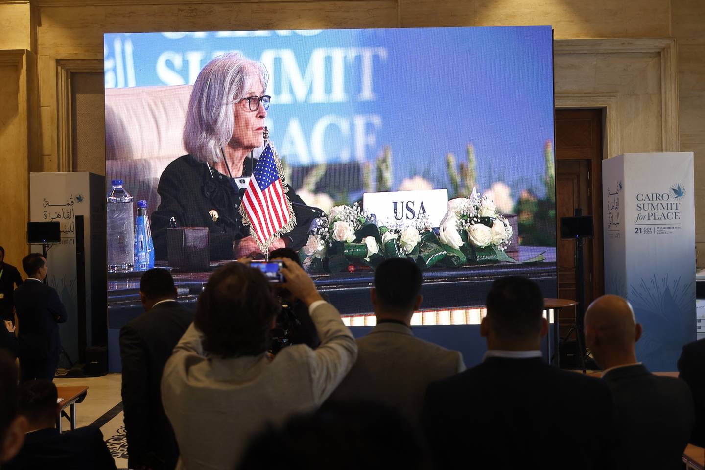 Los periodistas miran una pantalla grande que muestra a la encargada de negocios de Estados Unidos en Egipto, Beth Jones, asistiendo a la Cumbre Internacional de Paz