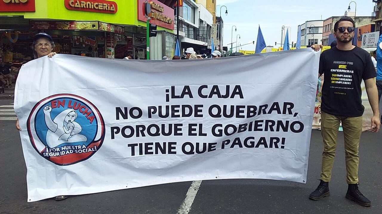 Sin identificar si representaban a algún sindicato, dos participantes llevaban una manta para exigir el pago a la CCSS. Foto: Magdalena López