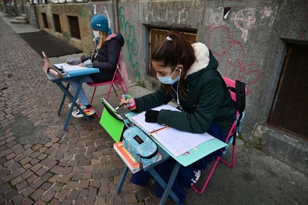 Anita Iacovelli (izq.) y su amiga Lisa Rogliatti, ambas de 12 años, se sientan frente a la escuela Italo Calvino, en Turín, como medida de protesta por las restricciones del gobierno sobre la pandemia. Foto: AFP
