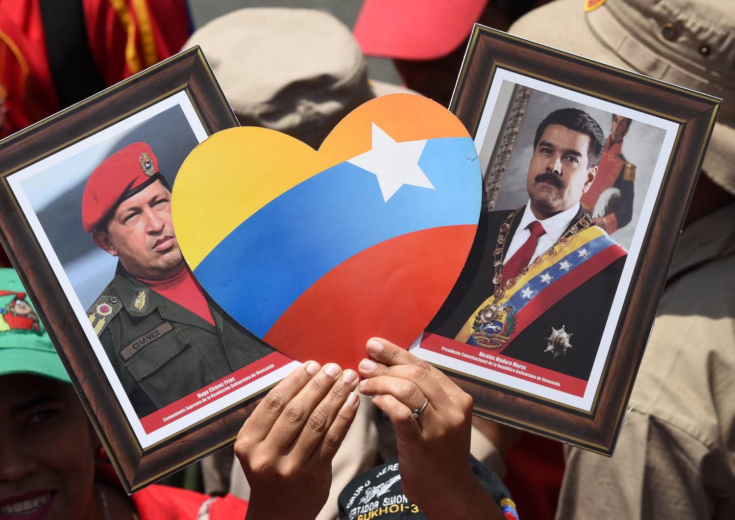 Un partidario del presidente venezolano, Nicolás Maduro, muestra fotografías de Maduro (der) y del difunto líder Hugo Chávez durante una manifestación.