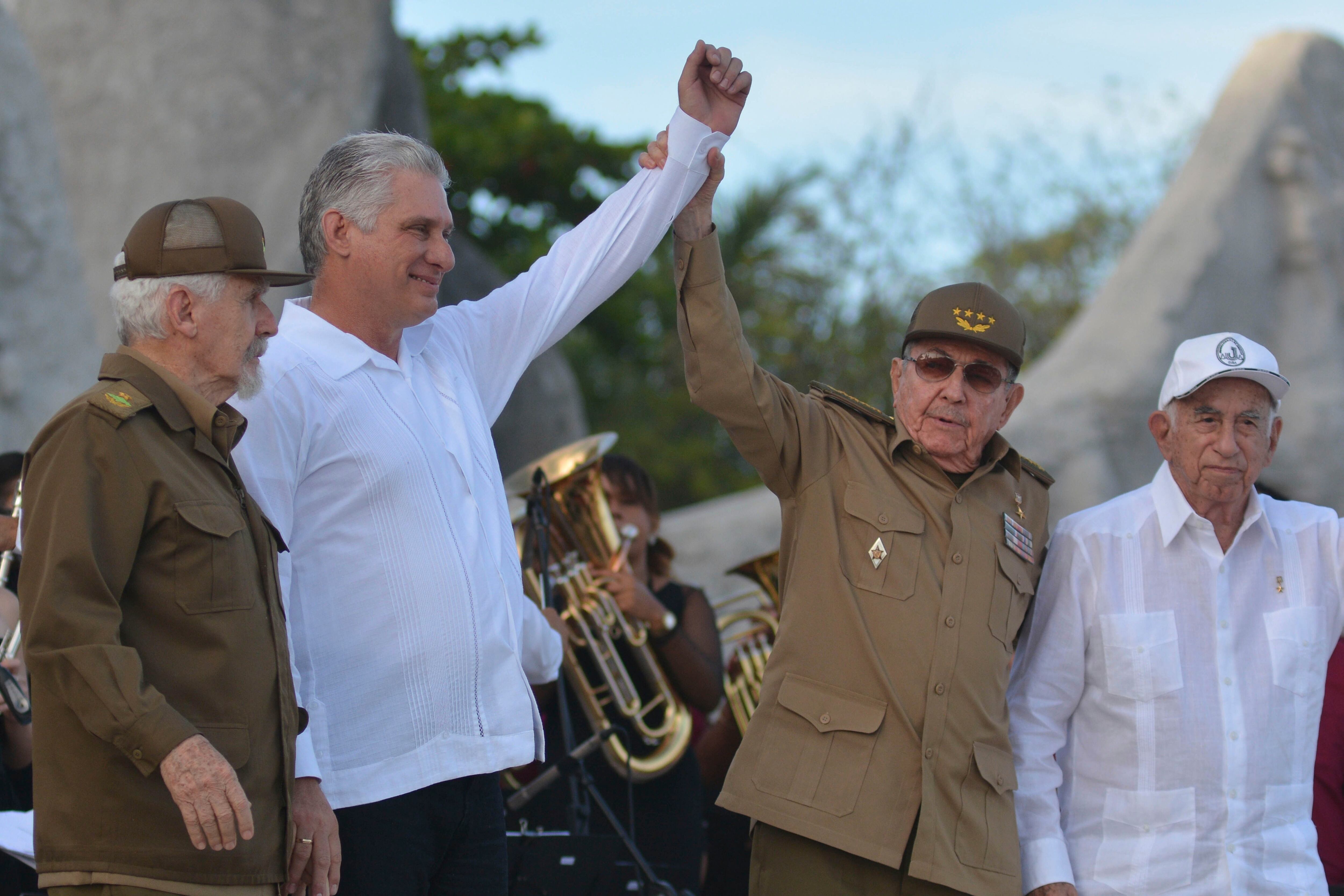 Miguel Díaz-Canel (segundo a la izquierda), y el exmandatario, Raúl Castro, alzan sus brazos durante la celebración del Día de la Revolución, en Bayamo, Cuba. Ambos figuran como posibles candidatos. 