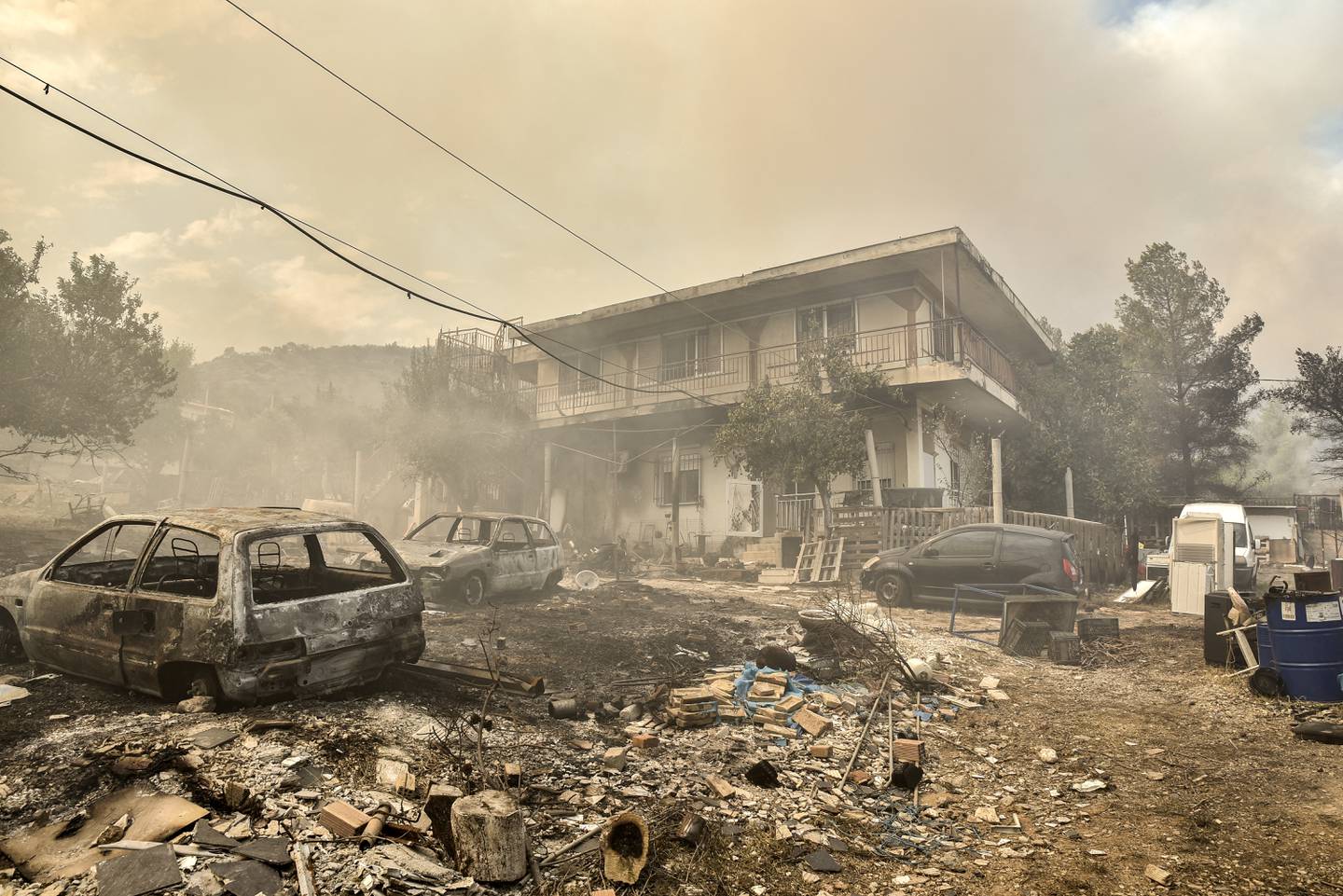 Esta fotografía tomada este 23 de agosto  muestra autos quemados cerca de una casa, tras los incendios forestales.