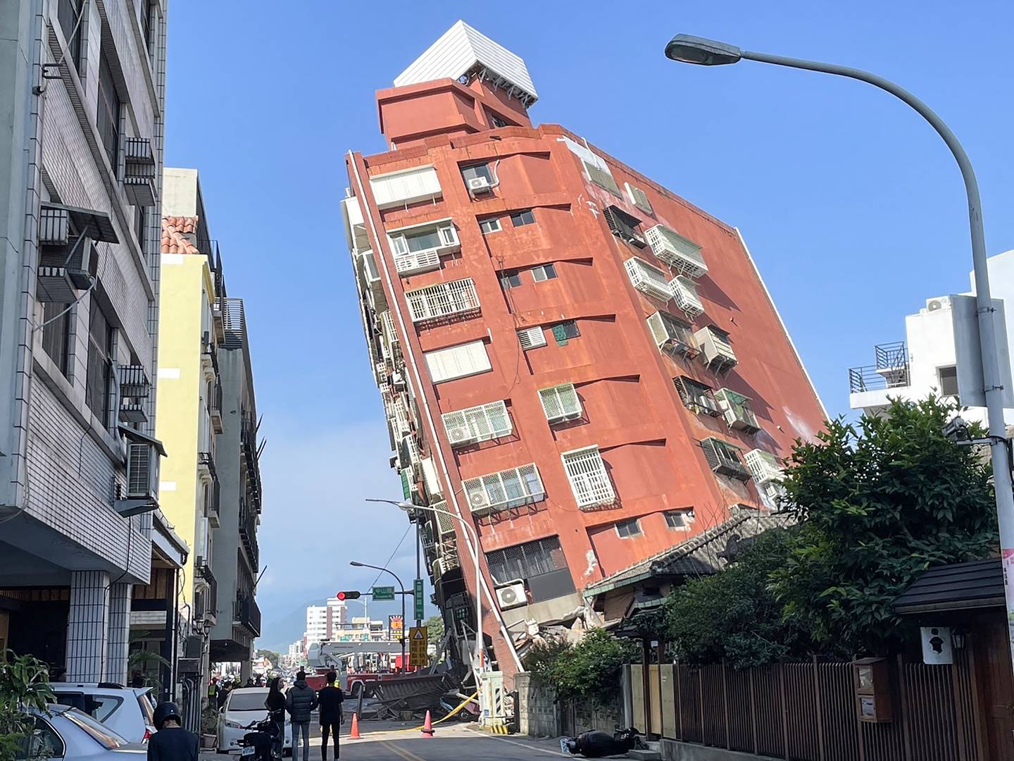 Esta foto tomada por la Agencia Central de Noticias de Taiwán (CNA) el 3 de abril de 2024 muestra a personas mirando un edificio dañado en Hualien, después de que un gran terremoto azotara el este de Taiwán. Un gran terremoto de magnitud 7,4 sacudió el este de Taiwán en la mañana del 3 de abril, lo que provocó advertencias de tsunami para la isla autónoma, así como para partes del sur de Japón y Filipinas. (Foto de CNA / AFP) / China FUERA - Macao FUERA - Taiwán FUERA / HONG KONG FUERA - RESTRINGIDO A USO EDITORIAL