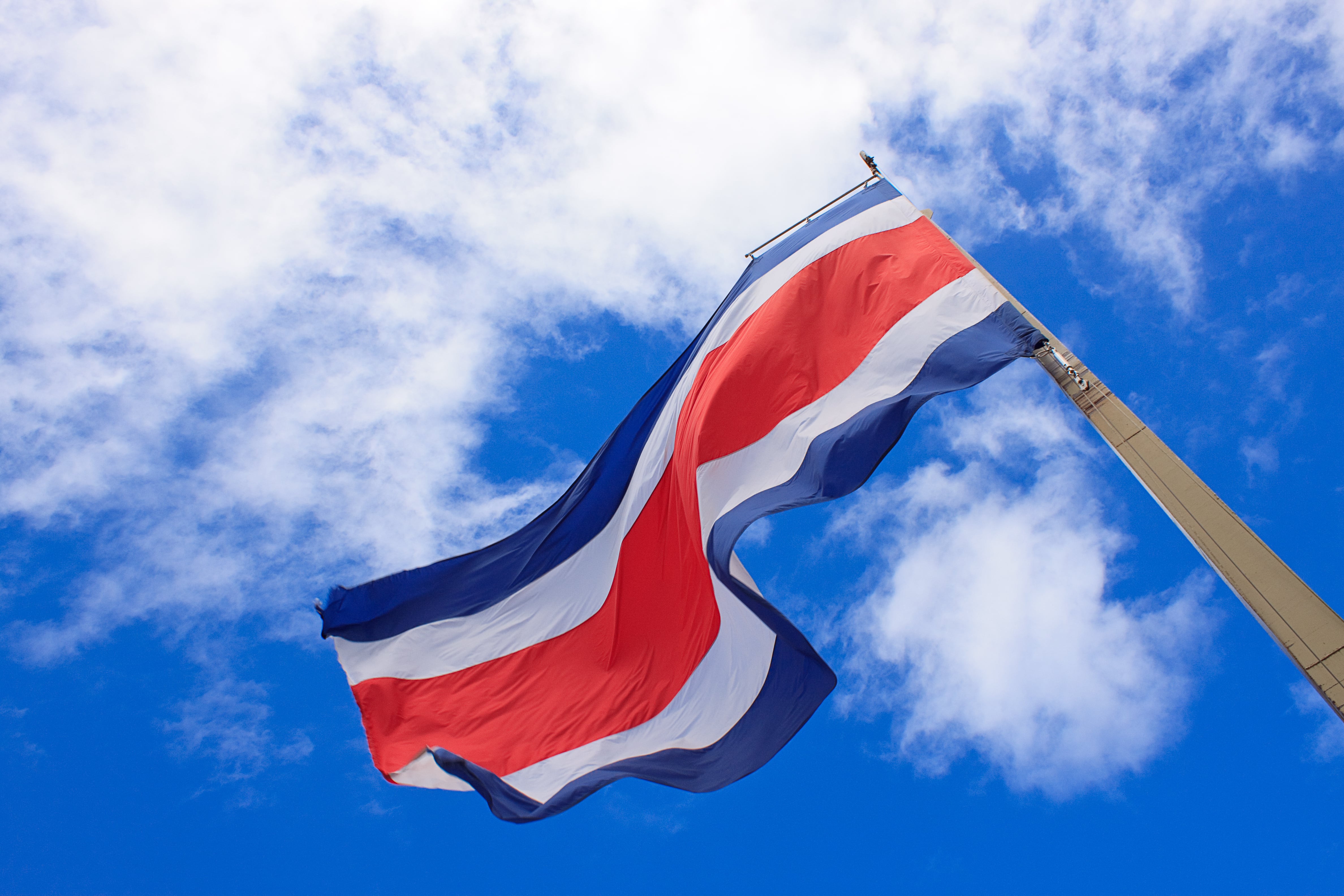 Bandera de Costa Rica ondeando con el cielo azul con nubes de fondo