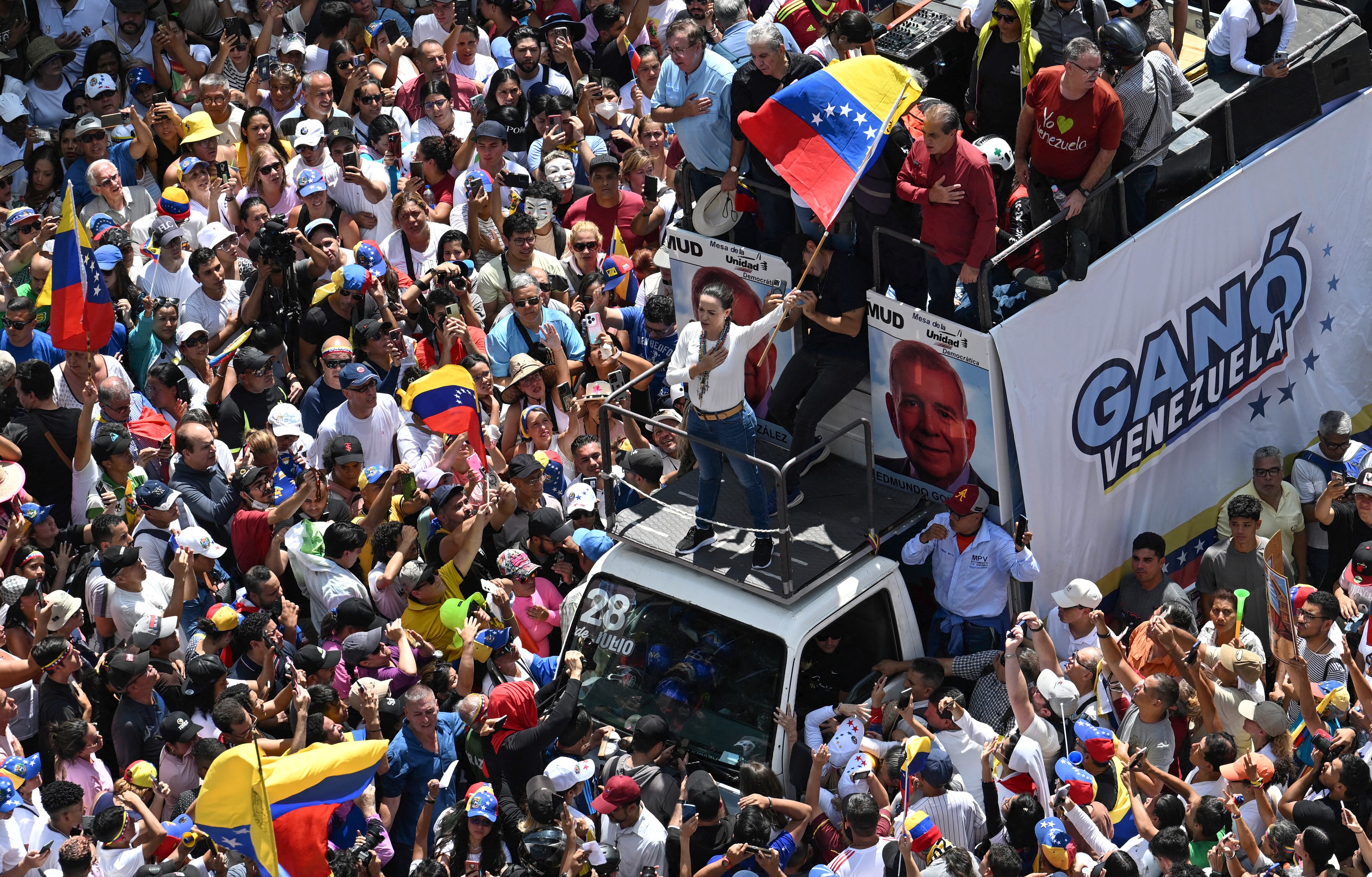 La líder opositora venezolana María Corina Machado (centro) ondea una bandera nacional desde lo alto de un camión durante una protesta convocada por la oposición para que se reconozca la victoria electoral, en Caracas, el 17 de agosto de 2024. Fotografía: