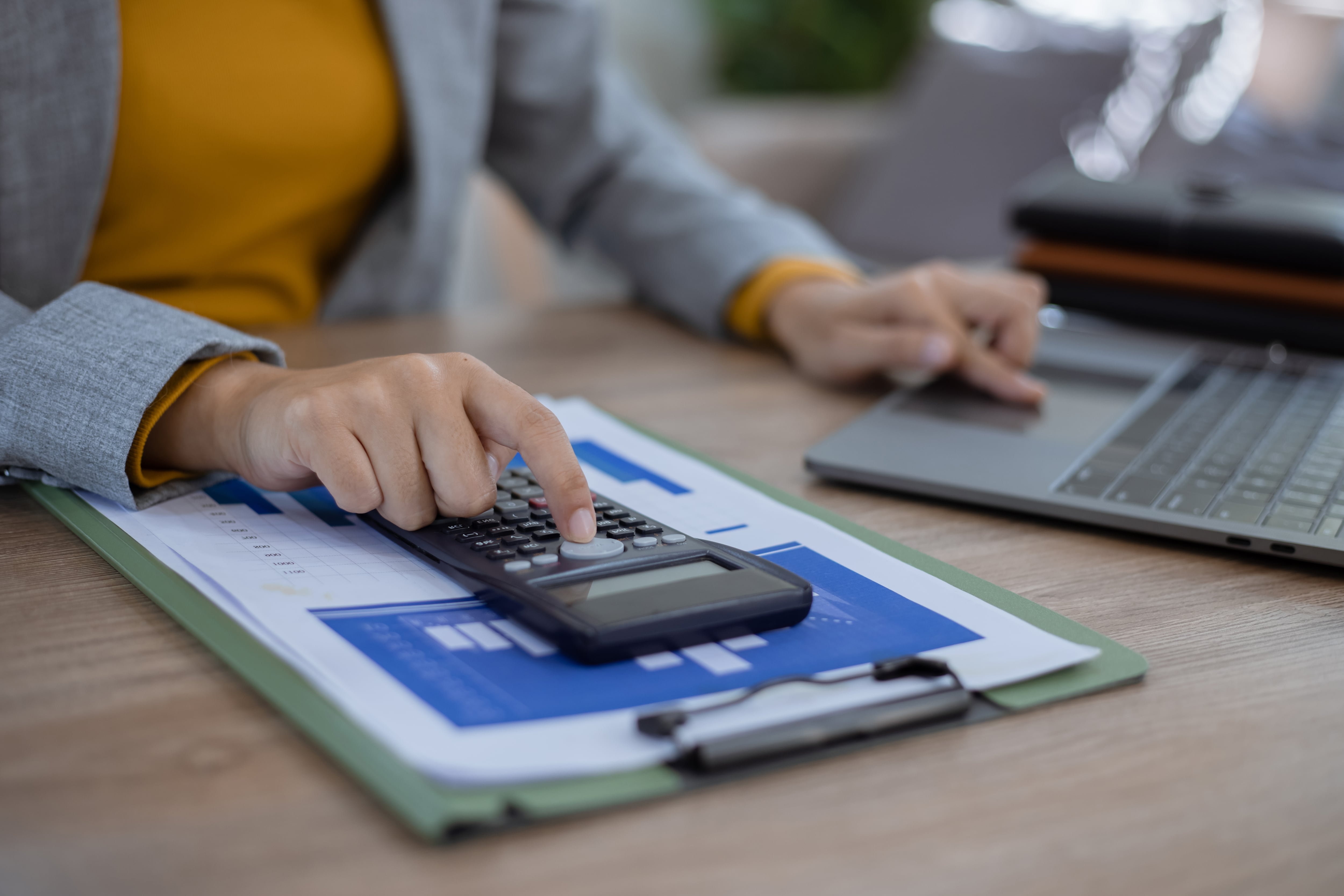 En la imagen alguien con una calculadora y una computadora