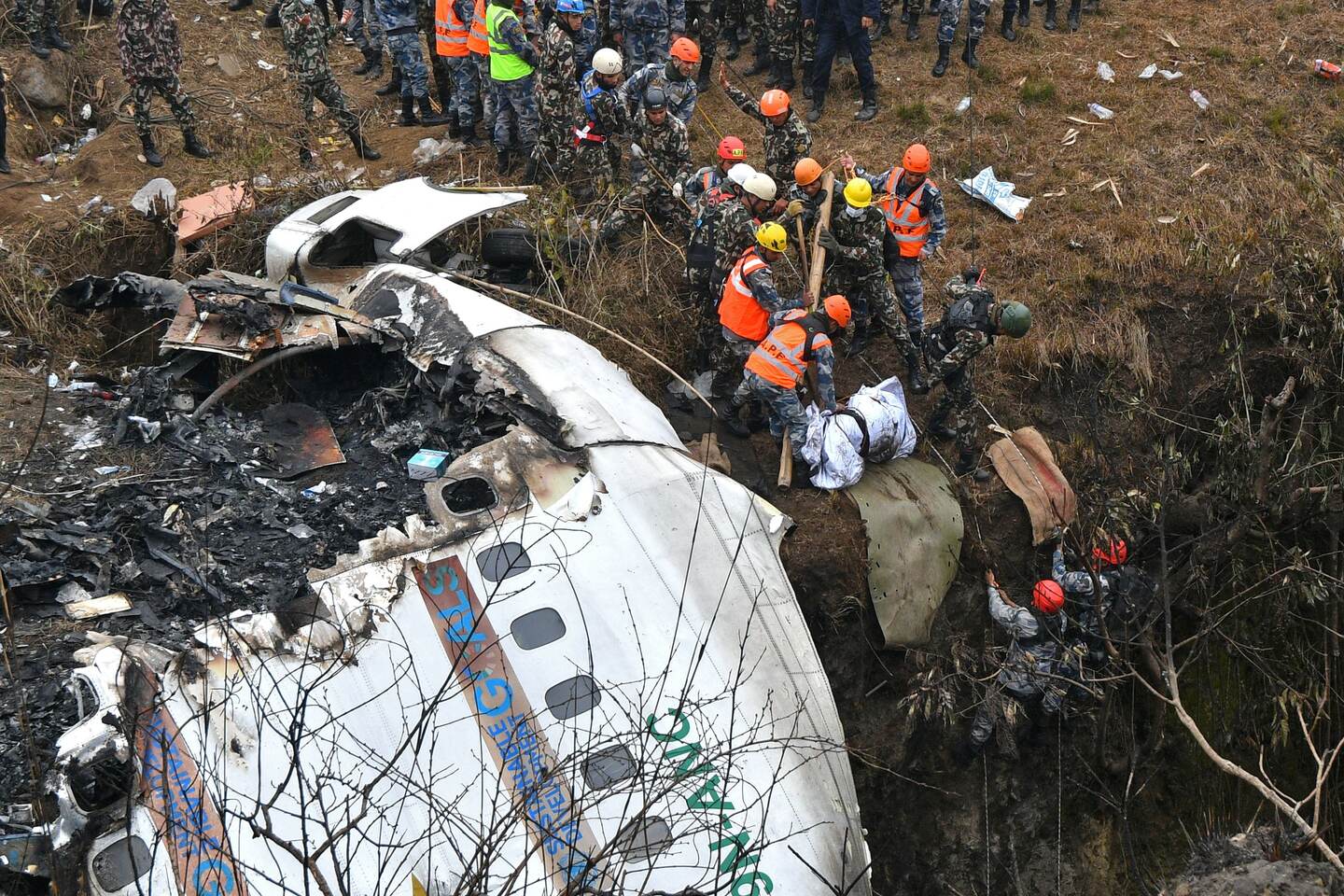 EDITORS NOTE: Graphic content / Rescuers pull the body of a victim who died in a Yeti Airlines plane crash in Pokhara on January 16, 2023. - Nepal observed a day of mourning on January 16 for the victims of the nation's deadliest aviation disaster in three decades, with 67 people confirmed killed in the plane crash. (Photo by PRAKASH MATHEMA / AFP)