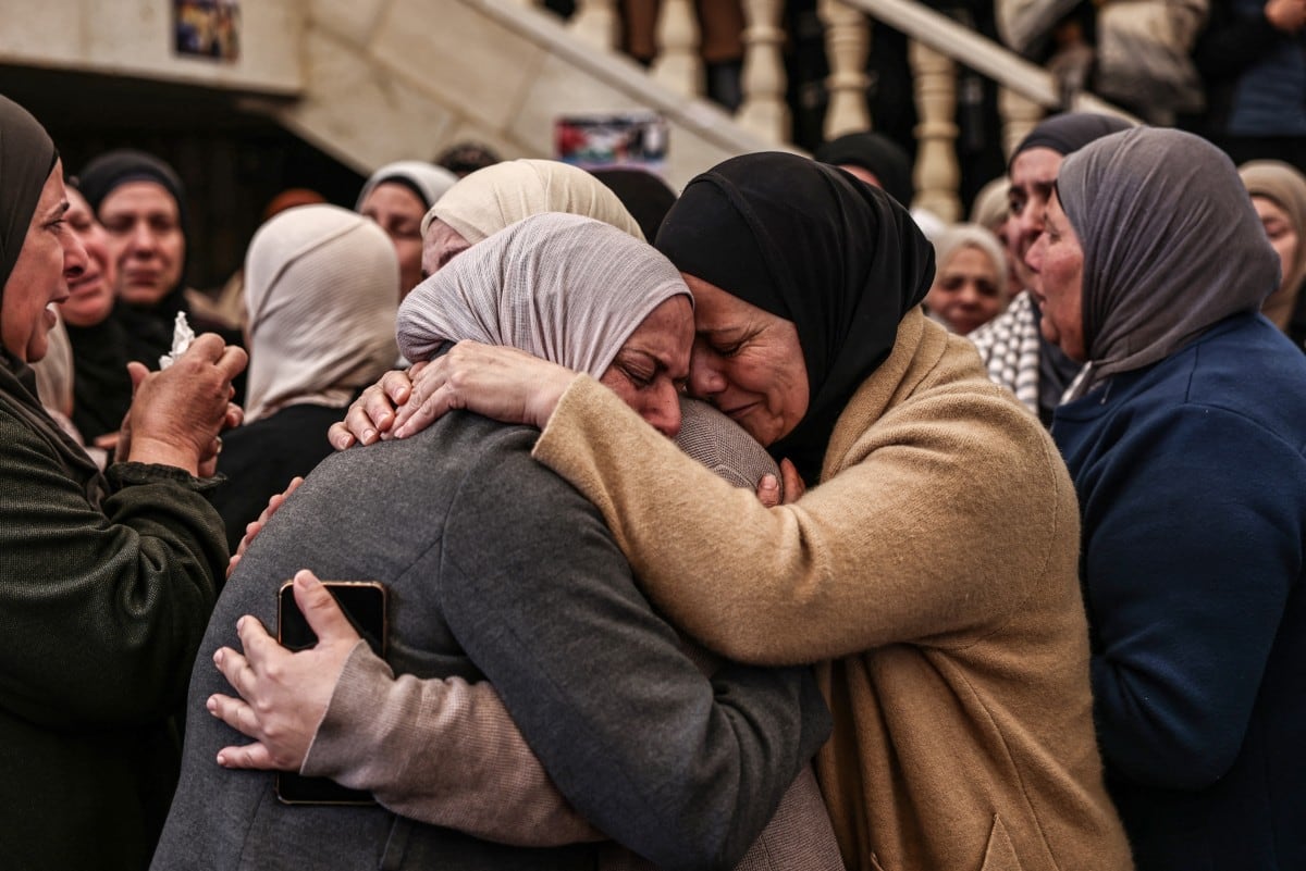 Familiares y amigas consuelan unas a otras durante el funeral de Ali Majed Hamadneh, de 23 años, en el pueblo de Deir Jarir, al noreste de la ciudad de Ramala, en la Cisjordania palestina ocupada por Israel, el 13 de abril de 2026.