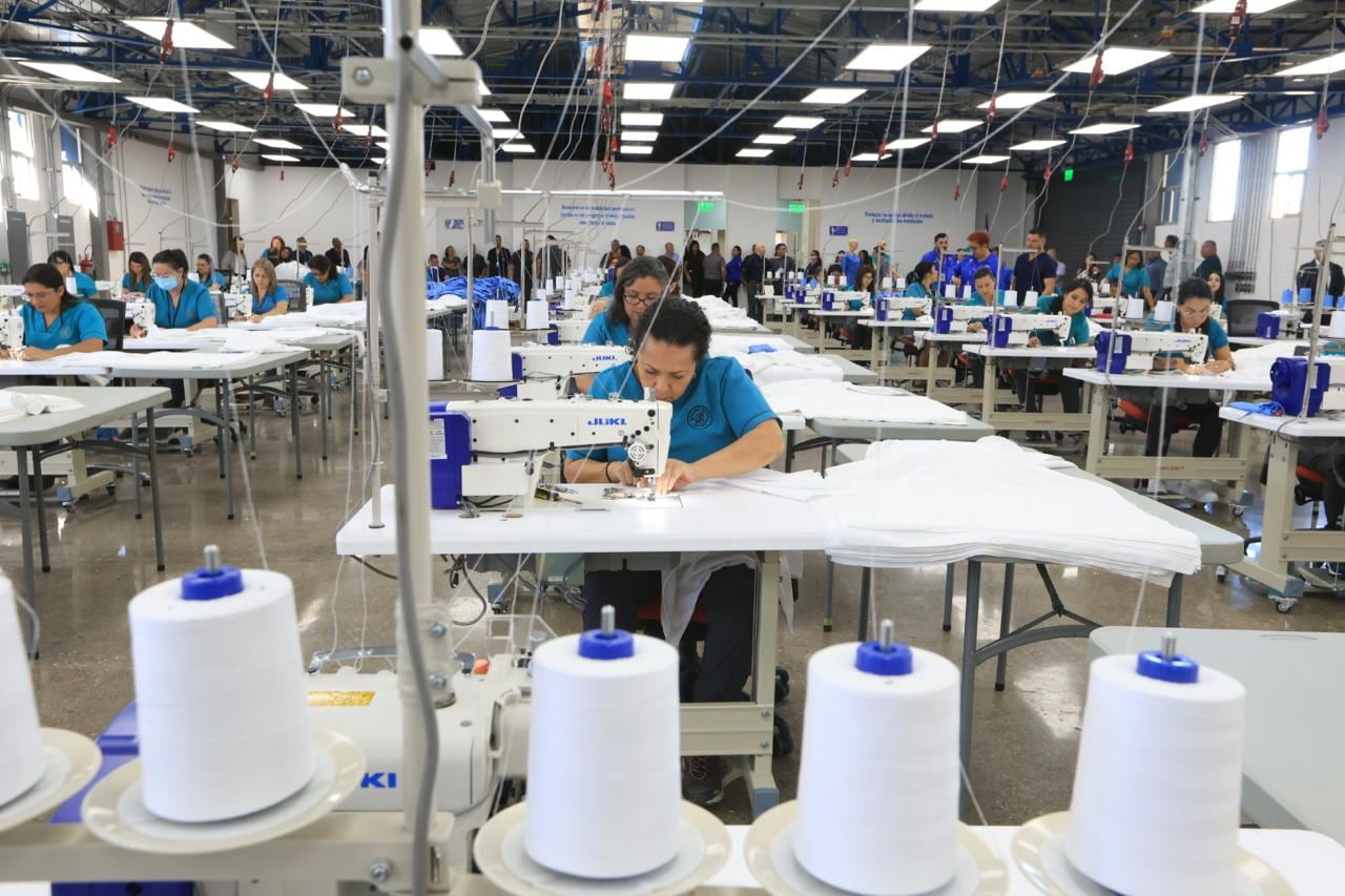 Gran salón con máquinas de coser y costureras en una fábrica industrial de ropa hospitalaria