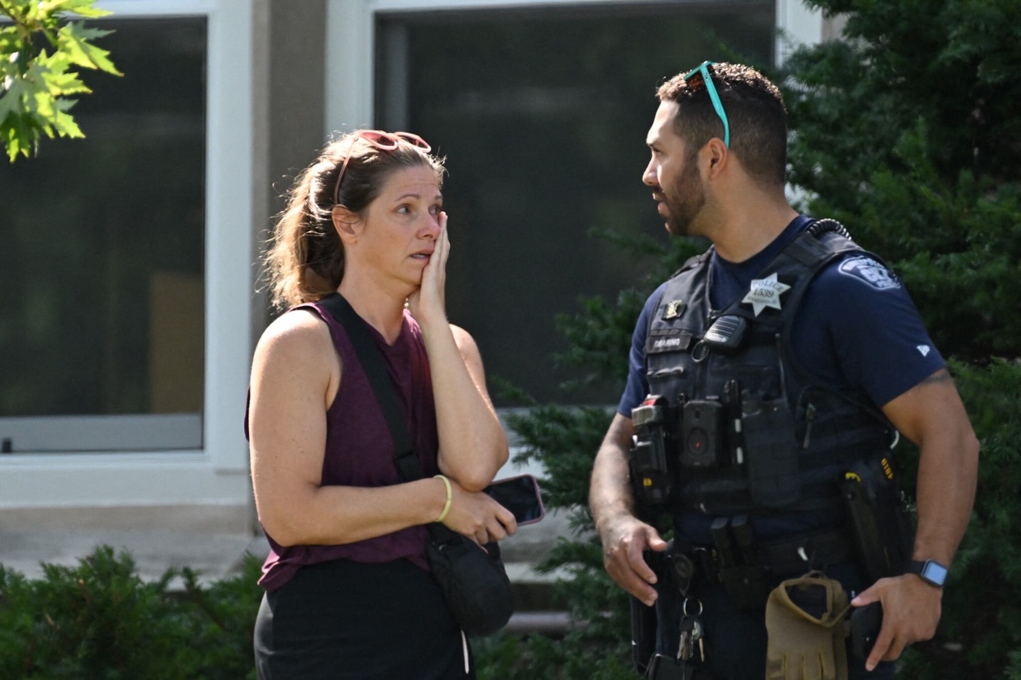 A woman speaks to a police officer near the scene of a shooting near Annunciation Catholic School in Minneapolis, Minneosta, on August 27, 2025. Two children were shot dead when a gunman attacked a Minneapolis church on Wednesday, with 17 people injured, 14 of them children, police said. The gunman "began firing a rifle through the church windows towards the children sitting in the pews at the mass," Minneapolis police chief Brian O'Hara told reporters. The pupils were marking the first week of the school year when the attack occurred. (Photo by Tom Baker / AFP)