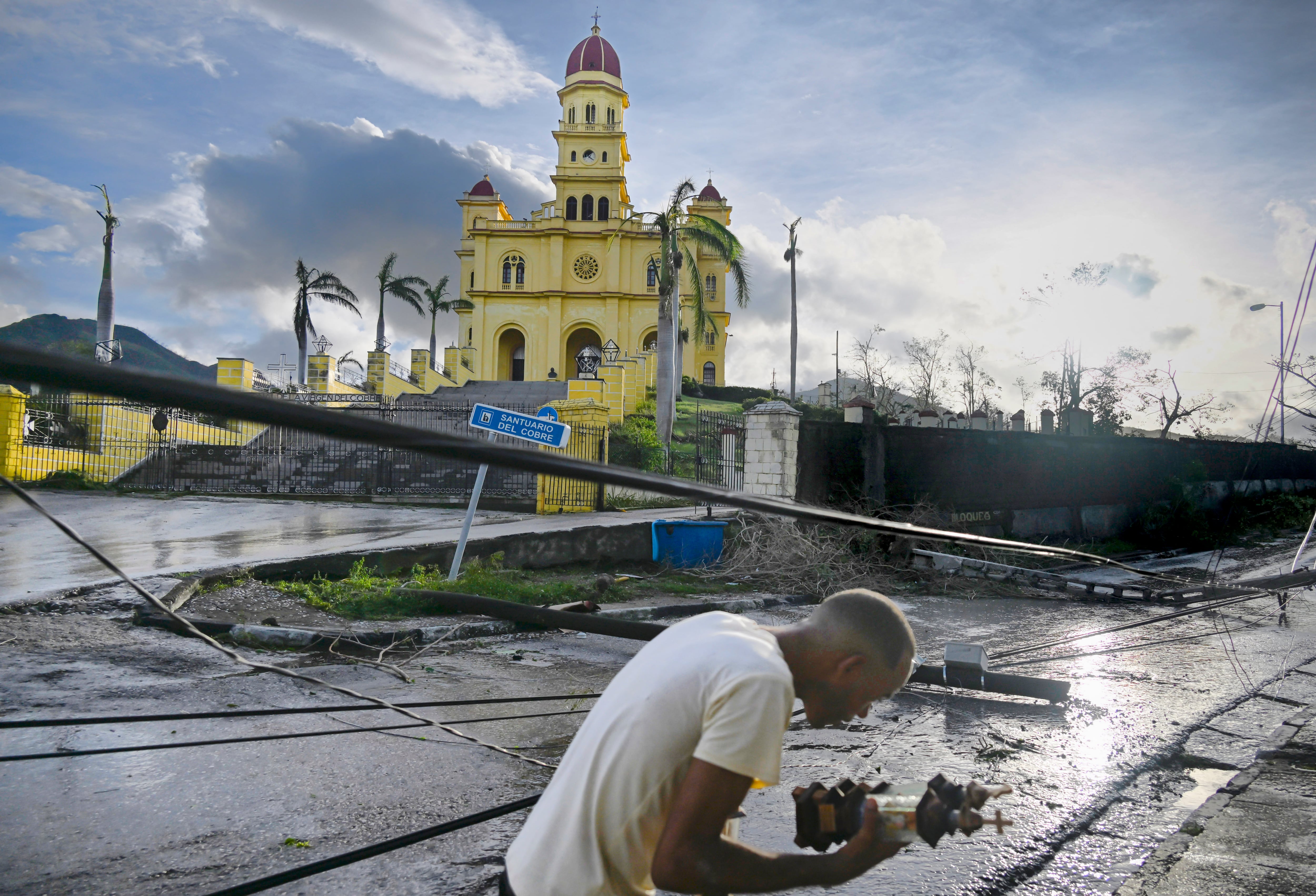 Un residente de El Cobre, en la provincia de Santiago de Cuba, limpió escombro junto a cables de electricidad caídos tras el paso del huracán Melissa, el 29 de octubre. Fotografía: