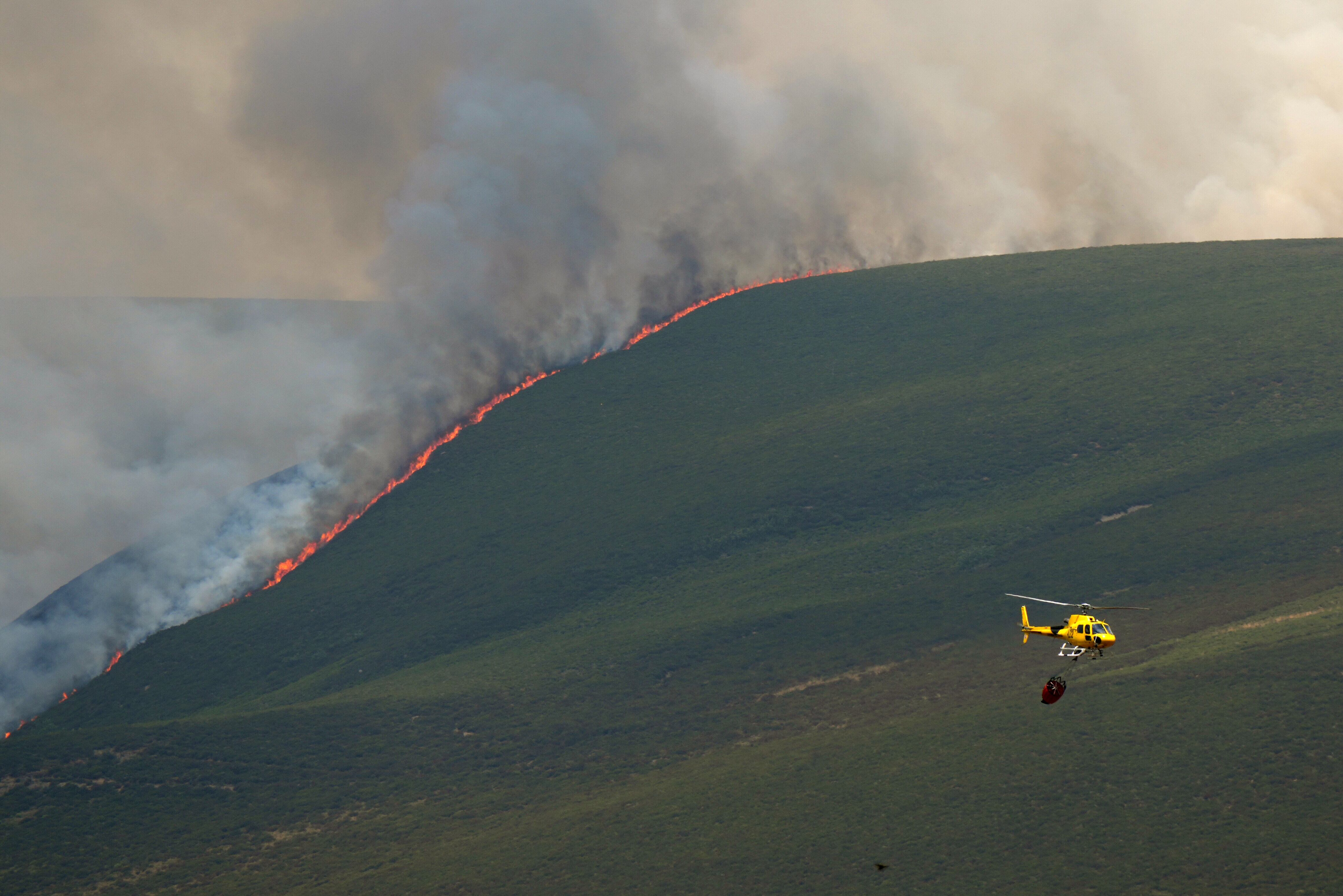 A helicopter fights a wildfire in Castrillo de Cabrera, northwestern Spain, on August 16, 2025. Spain, now in its third week under a heatwave alert, is still battling wildfires raging in the northwest and west of the country, where the army has been deployed to help contain the blazes. The regions of Castilla y Leon, Galicia, Asturias and Extremadura remain the hardest hit. (Photo by Cesar Manso / AFP)