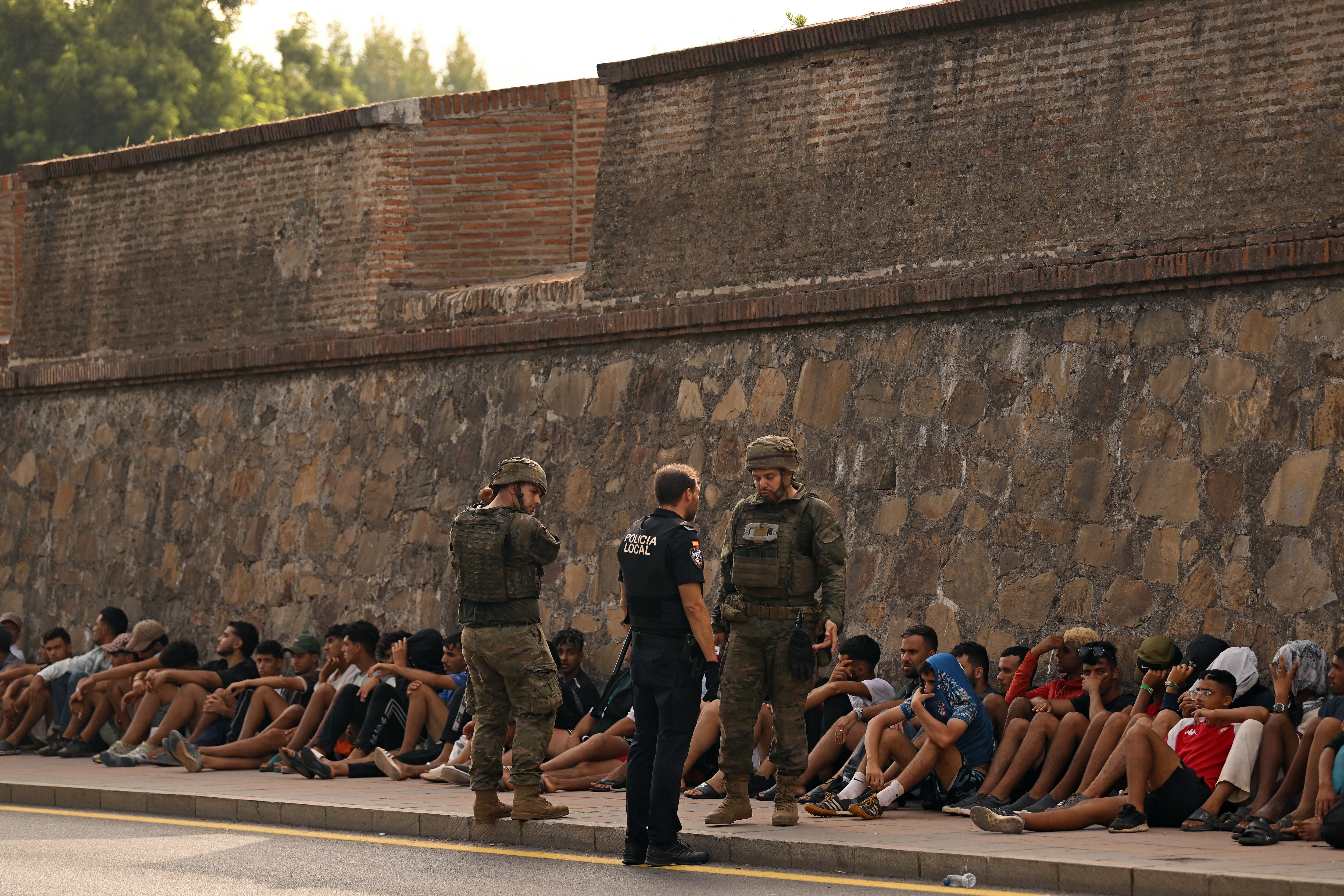 Soldados españoles custodian a migrantes antes de su retorno a Marruecos desde Ceuta, tras el ingreso de unas 60.000 personas al enclave español del norte de África.