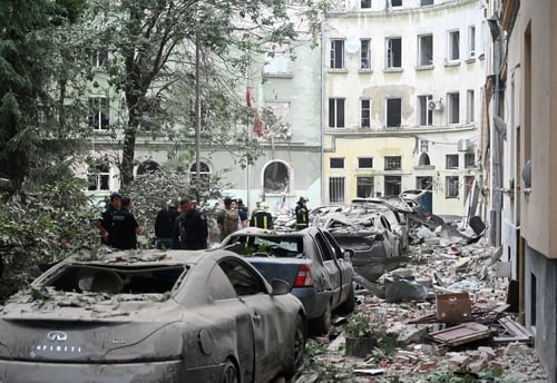 Edificios en ruinas y vehículos dañados en Lviv, Ucrania, como resultado del conflicto armado, evidenciando la destrucción en la ciudad.