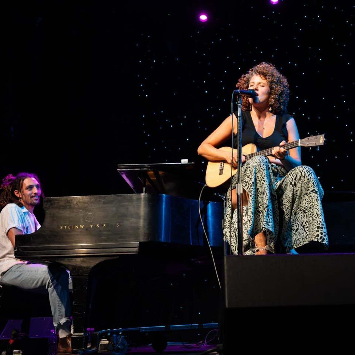 Imagen de la cantante franco dominicana Cyrille Aimée cantando mientras toca la guitarra.