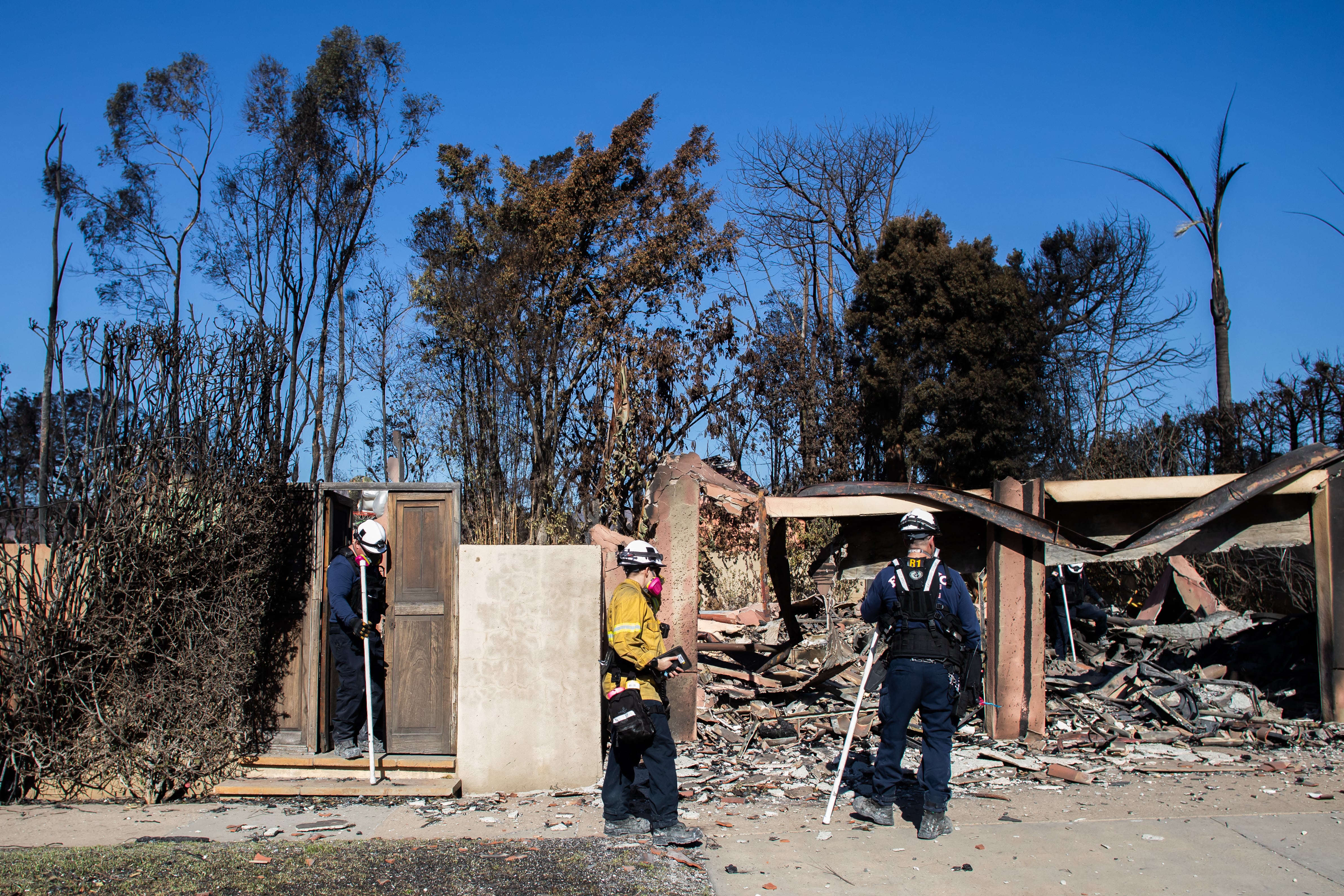 Los bomberos inspeccionan una casa quemada en el incendio Palisades. Más de 900 reclusos combaten incendios junto a bomberos en California.