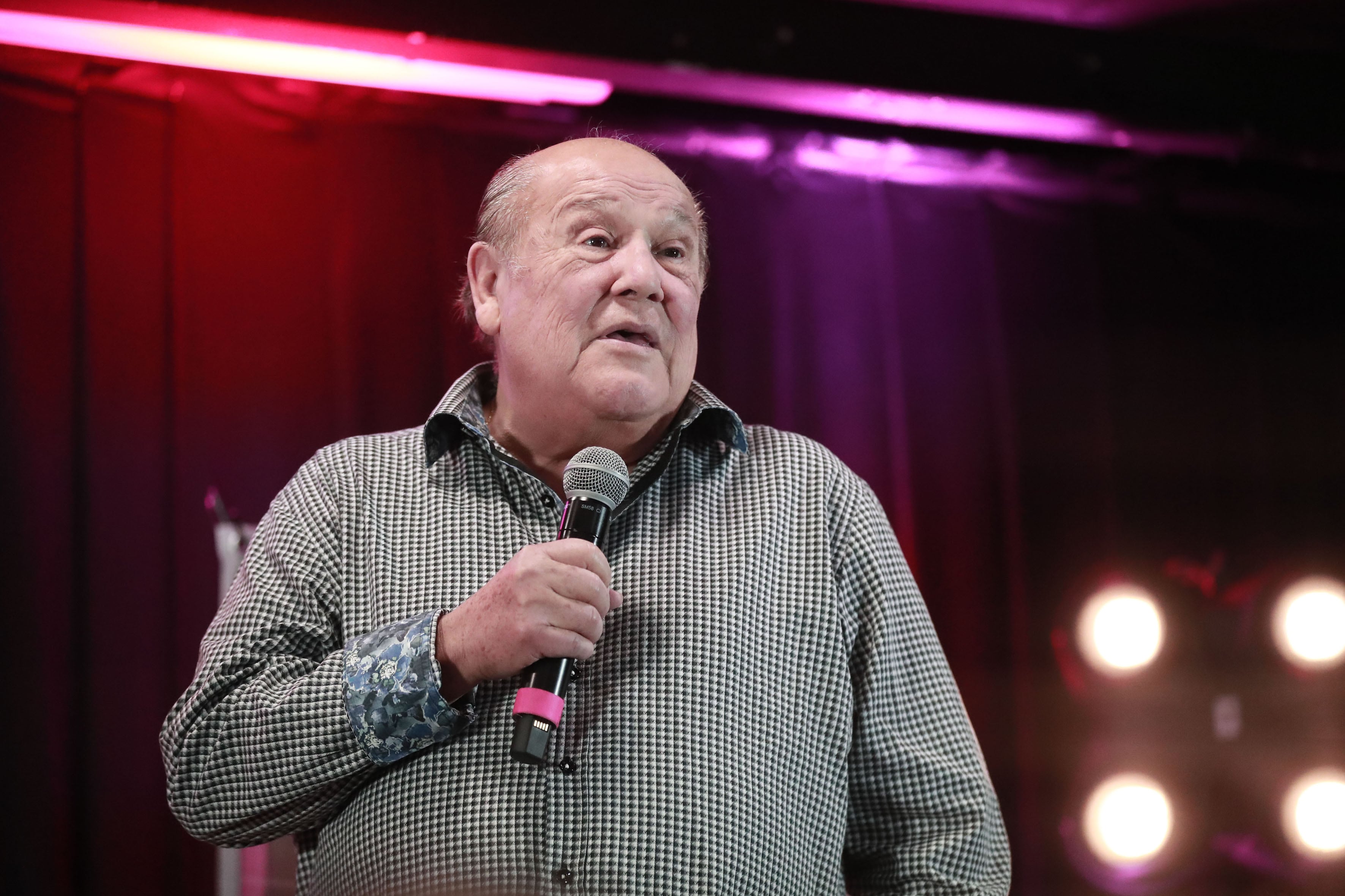 Imagen del cantante argentino Leo Dan sosteniendo un micrófono y vestido con una camisa de cuadros color negro con blanco.