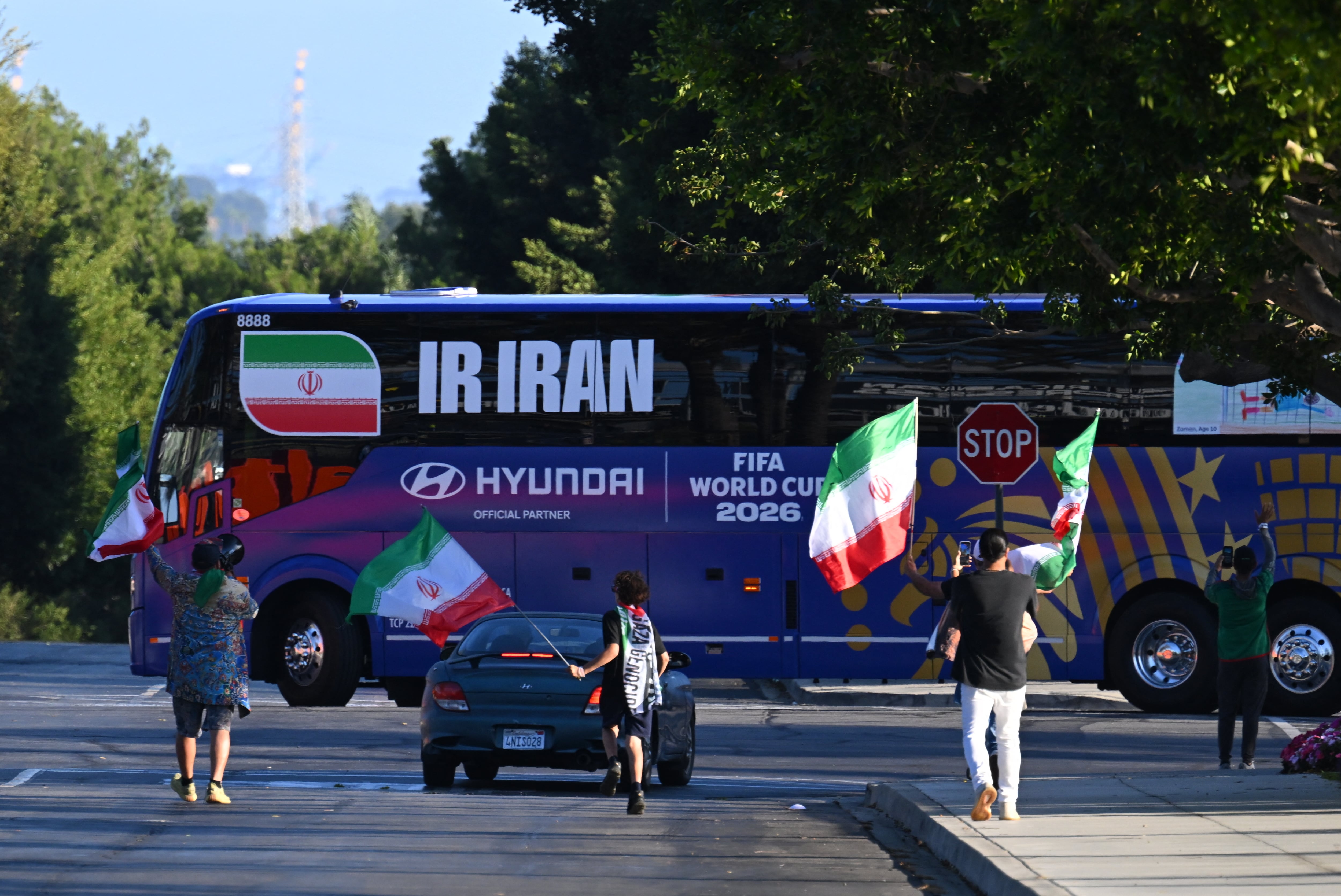 El bus de la Selección de Irán arriba al Carson Sports Park de Los Ángeles, donde debutarán en el Mundial 2026, mientras algunos aficionados ondean banderas en la calle.
