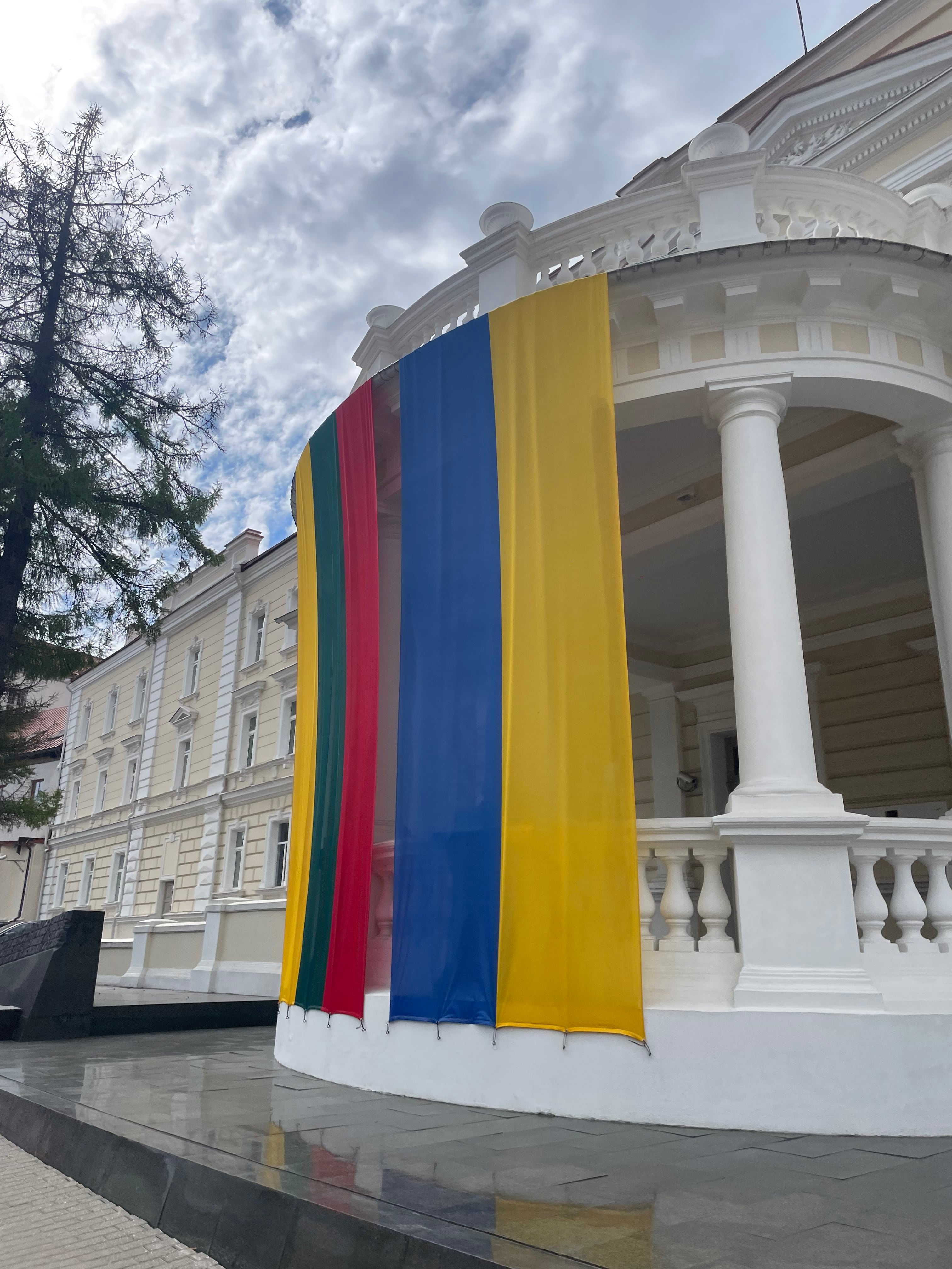 Fachada del Ministerio de Defensa de Lituania con la bandera patria y la ucraniana; fuera del cuadro, un inmenso rótulo celebrando a la OTAN recibe a los visitantes.