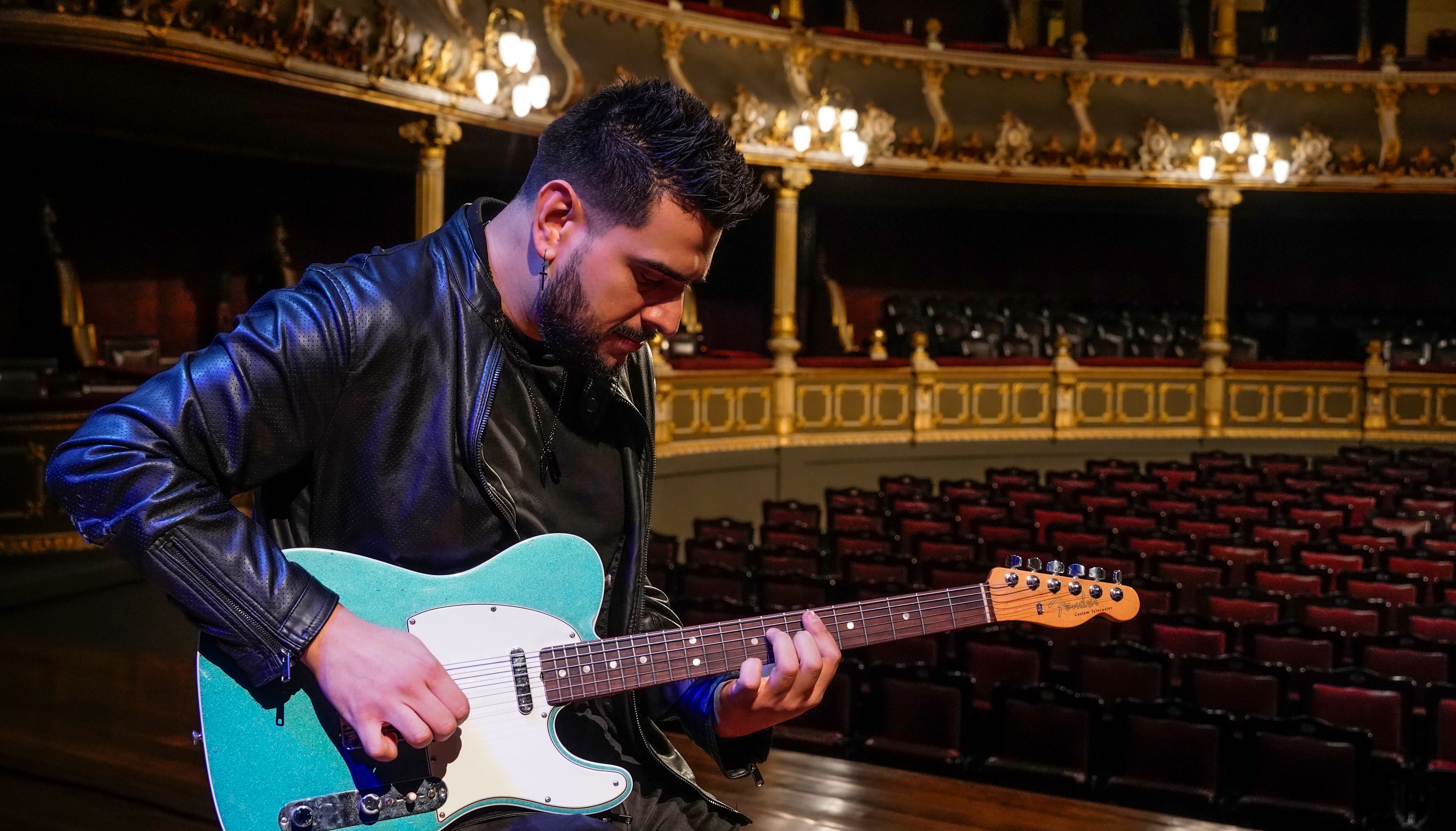 Músico tocando la guitarra en un teatro.