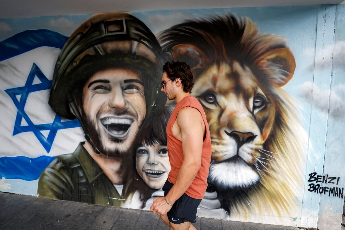 Un hombre pasa frente a un mural del artista urbano Benzi Brofman que representa a un soldado israelí, un niño y un león, en alusión al nombre de la operación de Israel "León Naciente" contra Irán, en una calle de la ciudad norteña de Haifa, Israel, el 17 de junio de 2025. (Foto: Jalaa MAREY / AFP) / USO EDITORIAL RESTRINGIDO – MENCIÓN OBLIGATORIA DEL ARTISTA AL PUBLICAR – PARA ILUSTRAR EL EVENTO SEGÚN LO INDICADO EN EL PIE DE FOTO.