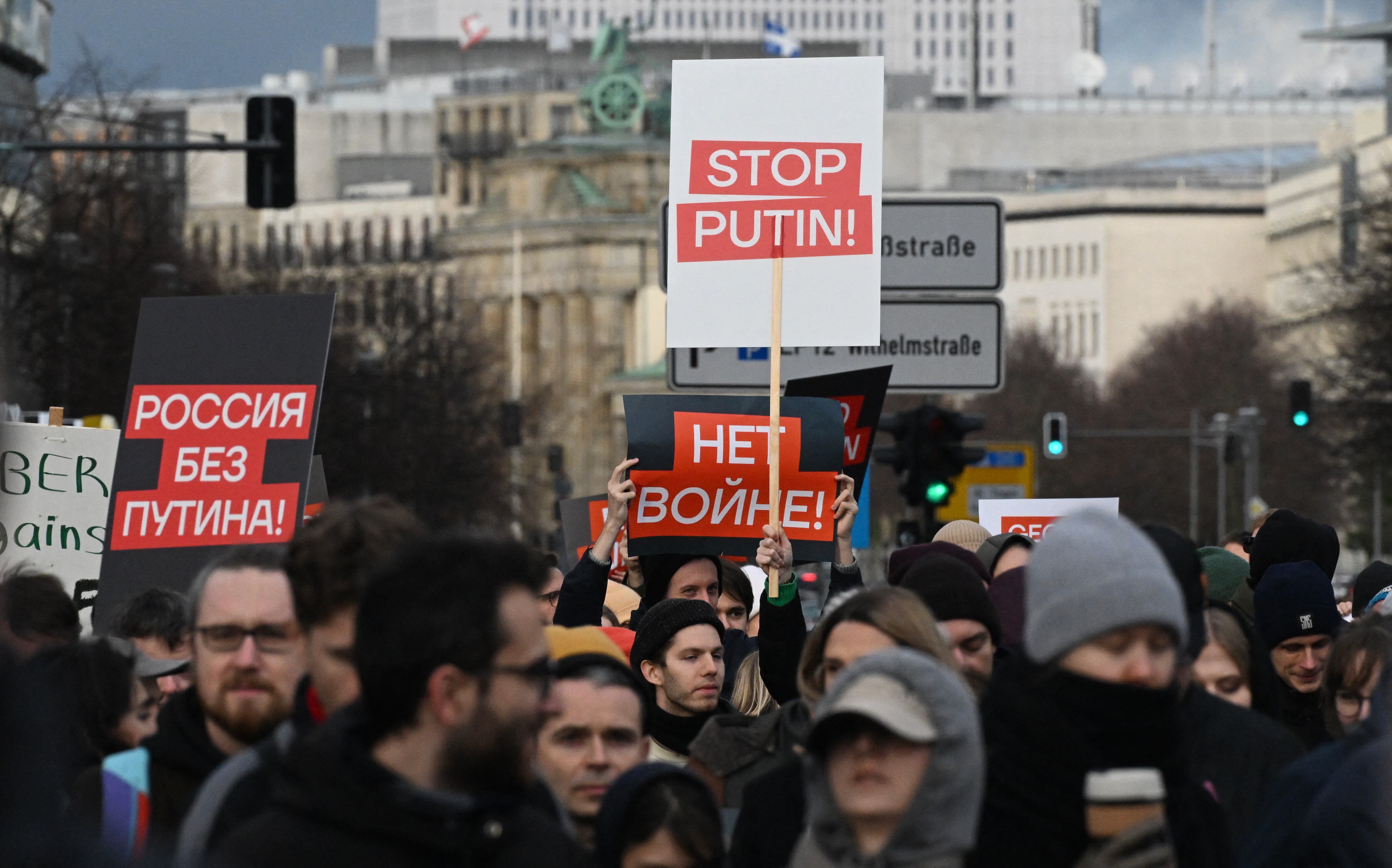 Manifestantes en Berlín levantan carteles con mensajes contra Putin y la guerra durante una protesta de la oposición rusa exiliada contra la invasión de Ucrania. Foto: RALF HIRSCHBERGER / AFP