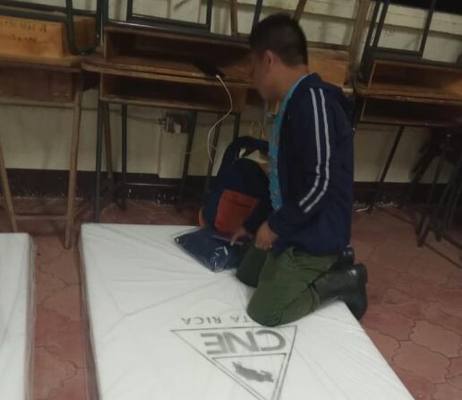 Un hombre acomoda sus pertenencias sobre una colchoneta otorgada por la CNE para el albergue de la escuela Ngöbegue.