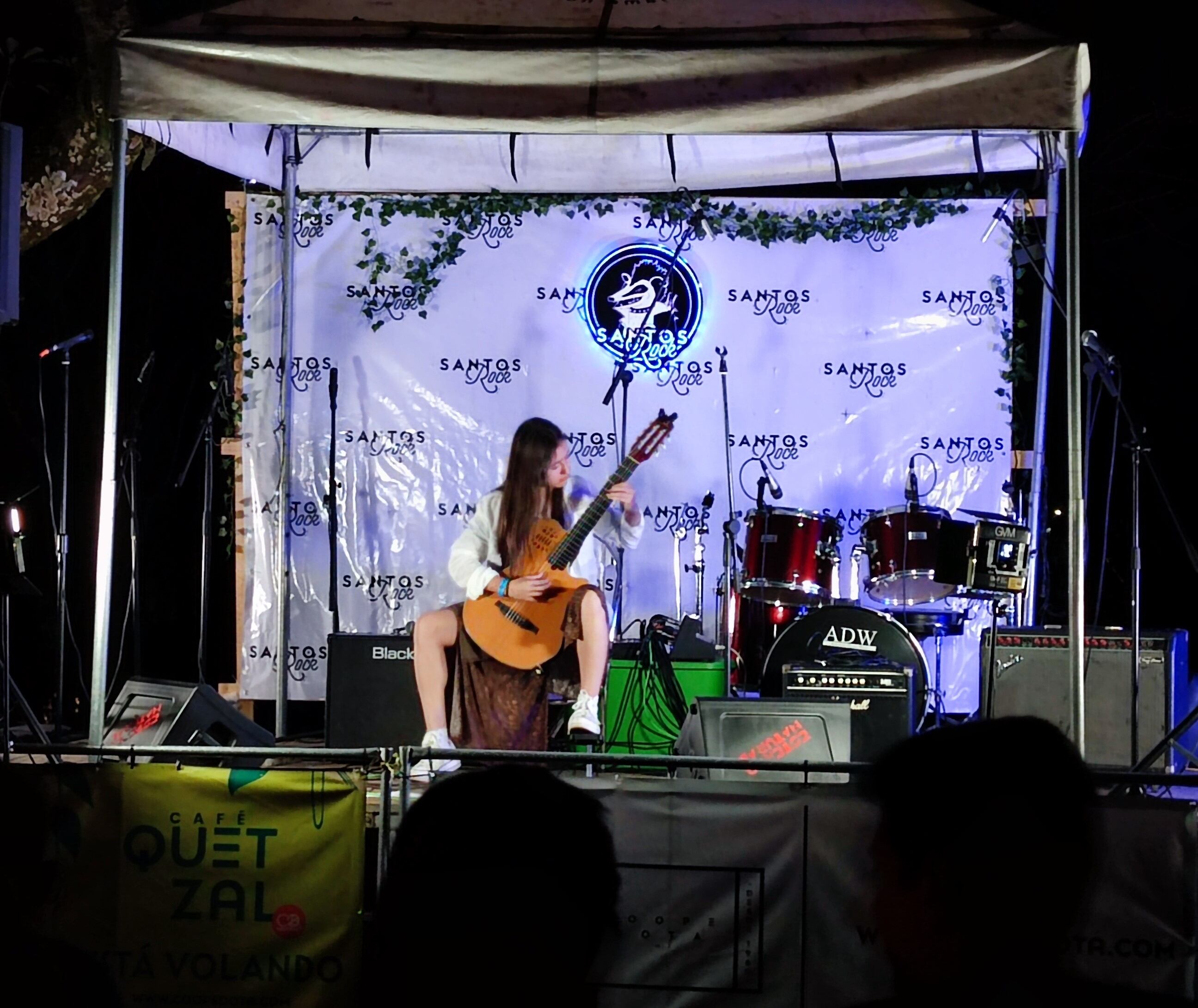 Imagen de una artista costarricense tocando su guitarra en el escenario del Santos Rock.