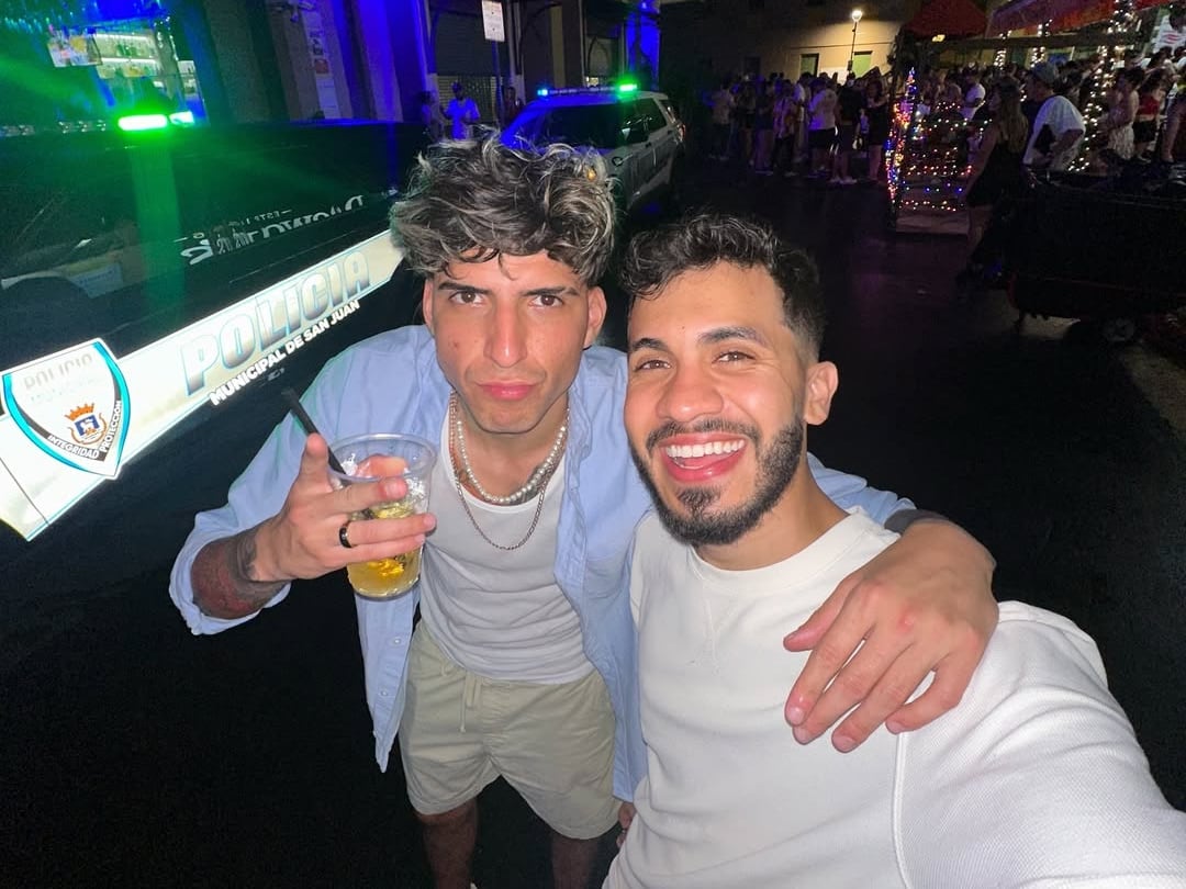 Julián Valverde a la izquierda con un vaso con una bebida alcohólica, abrazando a Araya Vlogs en un bar de Puerto Rico