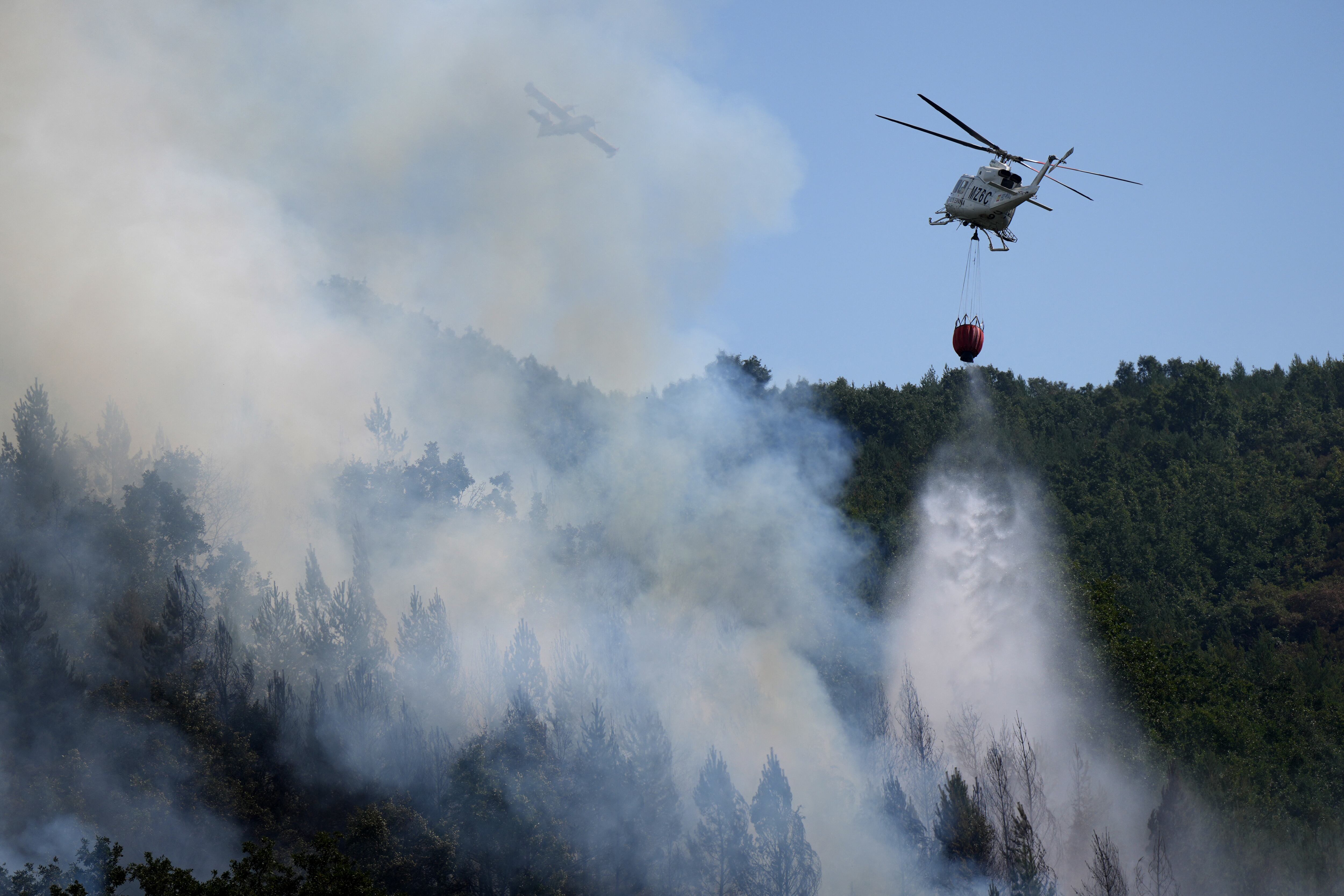 Un helicóptero de bomberos lanzando agua y un avión sobre un incendio forestal en Garano, cerca de León, noroeste de España, el pasado 25 de agosto. Fotografía: