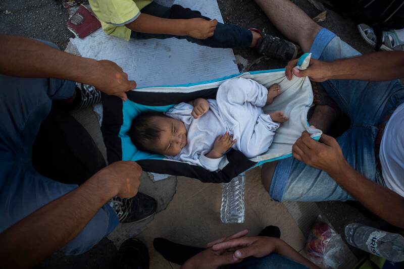 Refugiados afganos mecen a un bebé mientras esperan en el puerto de Mitilene, en la isla de Lesbos, a abordar un ferri hacia Atenas. | AP