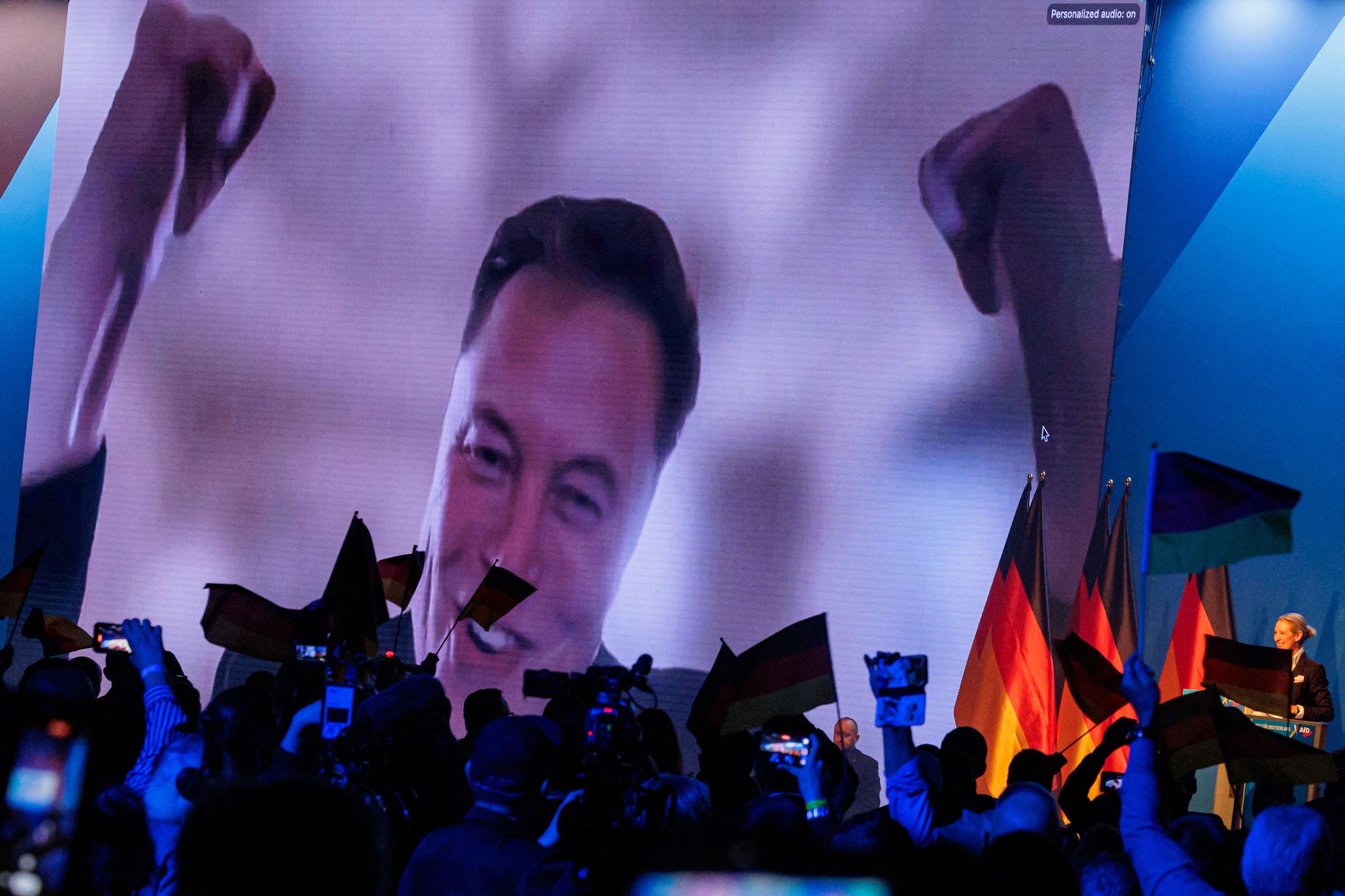 El multimillonario y empresario tecnológico estadounidense Elon Musk (izq.) aparece en una pantalla grande mientras Alice Weidel (der.), colíder del partido ultraderechista Alternativa para Alemania (AfD) de Alemania, se dirige a un mitin de campaña electoral en Halle, este de Alemania, el 25 de enero de 2025.