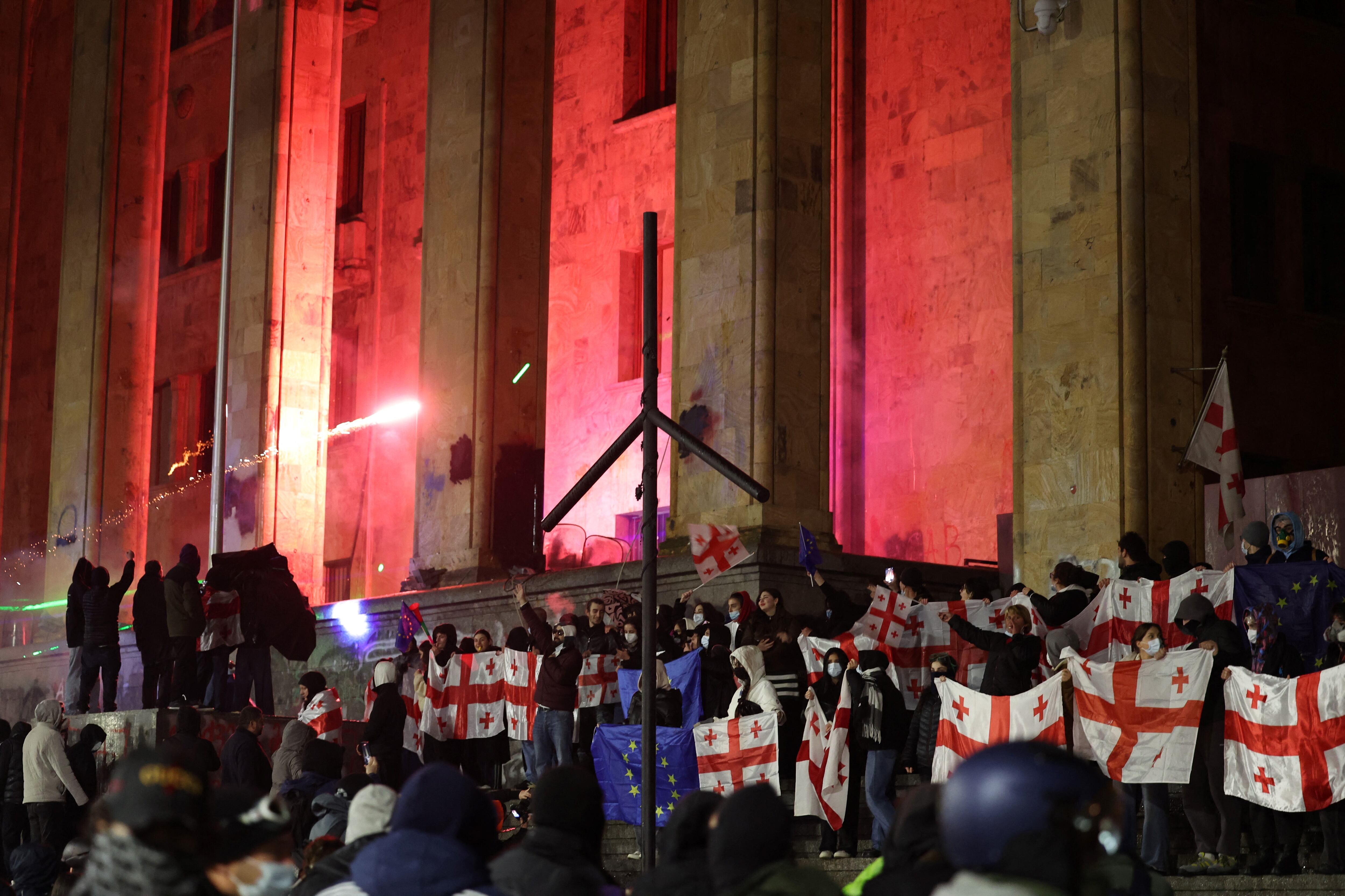 Manifestantes en Tbilisi sostienen banderas de Georgia durante una protesta frente al Parlamento contra la decisión del gobierno de posponer las conversaciones de adhesión a la UE, en medio de una crisis poselectoral, el 1 de diciembre de 2024.