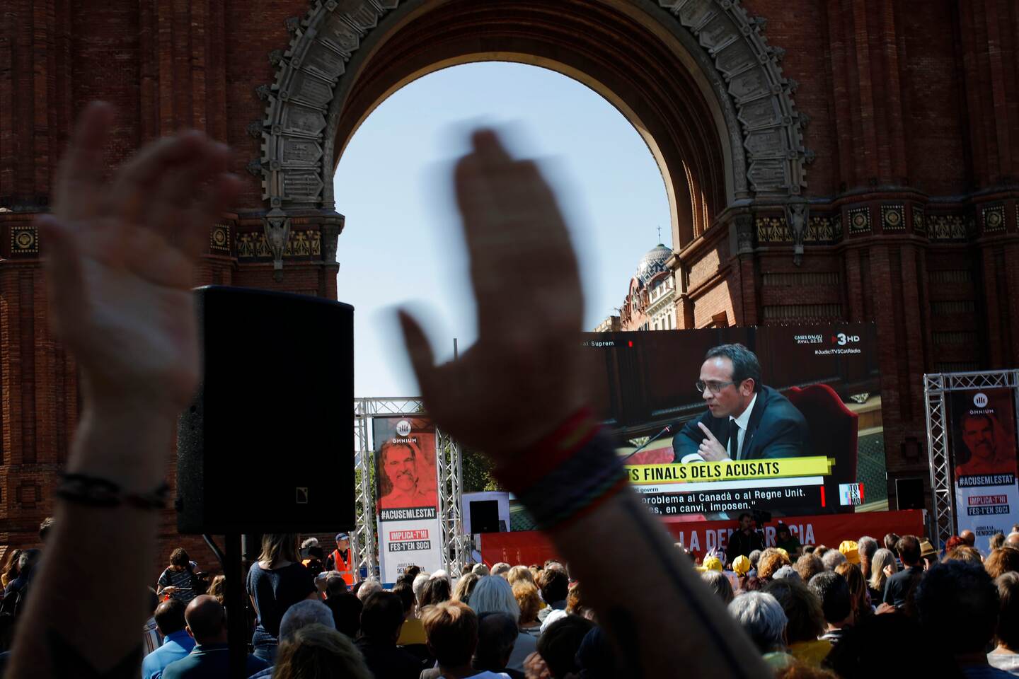 People look at a big TV screen showing the trial at Spain's Supreme Court happening Madrid on Wednesday, June 12, 2019, as they gather in downtown Barcelona, Spain. A dozen politicians and activists on trial for their failed bid in 2017 to carve out an independent Catalan republic in northeastern Spain will deliver their final statements Wednesday as four months of hearings draw to an end. (AP Photo/Emilio Morenatti)