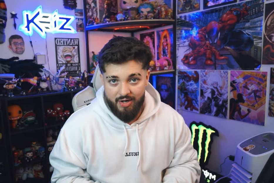 El 'influencer' costarricense Keiz en una de sus transmisiones. Se ve en un cuarto lleno de carteles, usa suéter de color blanco.