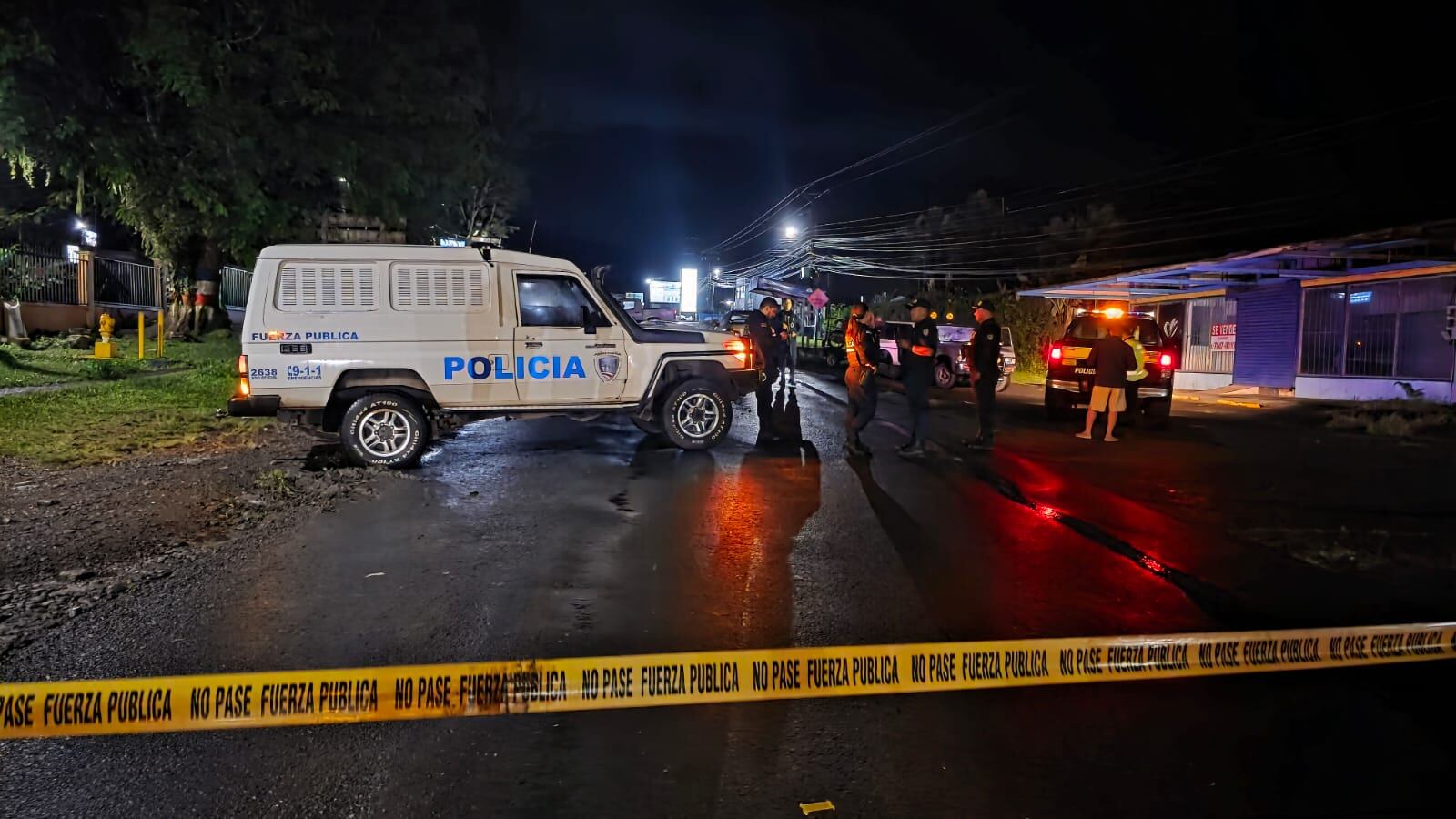 Calle cerrada, carros de la Fuerza Pública, cinta amarilla. Policías revisando la escena.