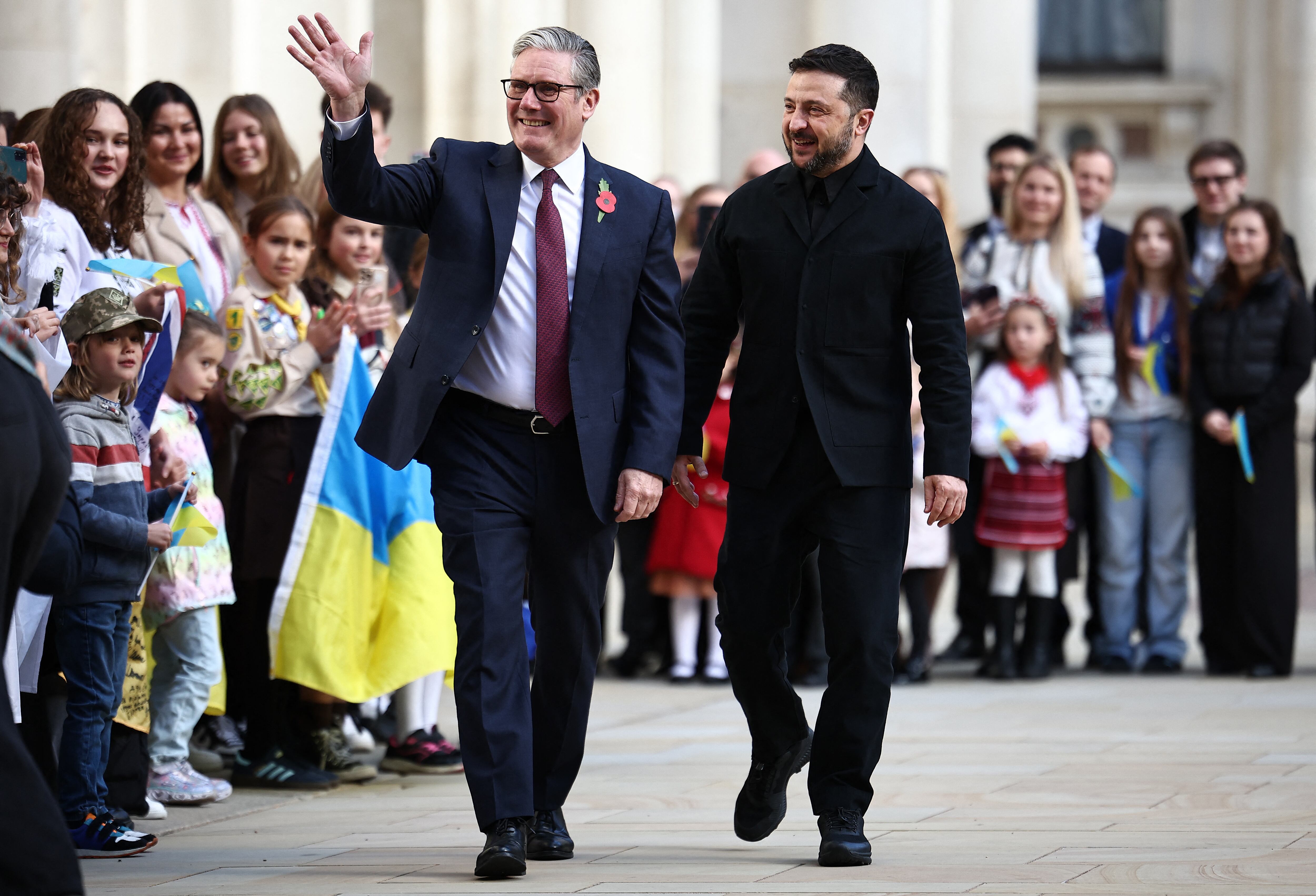 El primer ministro británico, Keir Starmer, (izq.) y el presidente ucraniano, Volodímir Zelenski, son recibidos por escolares ucranianos a su llegada al Ministerio de Asuntos Exteriores, de la Commonwealth y de Desarrollo (FCDO) para una reunión de la Coalición de la Voluntad, en el centro de Londres este 24 de octubre. Fotografía: