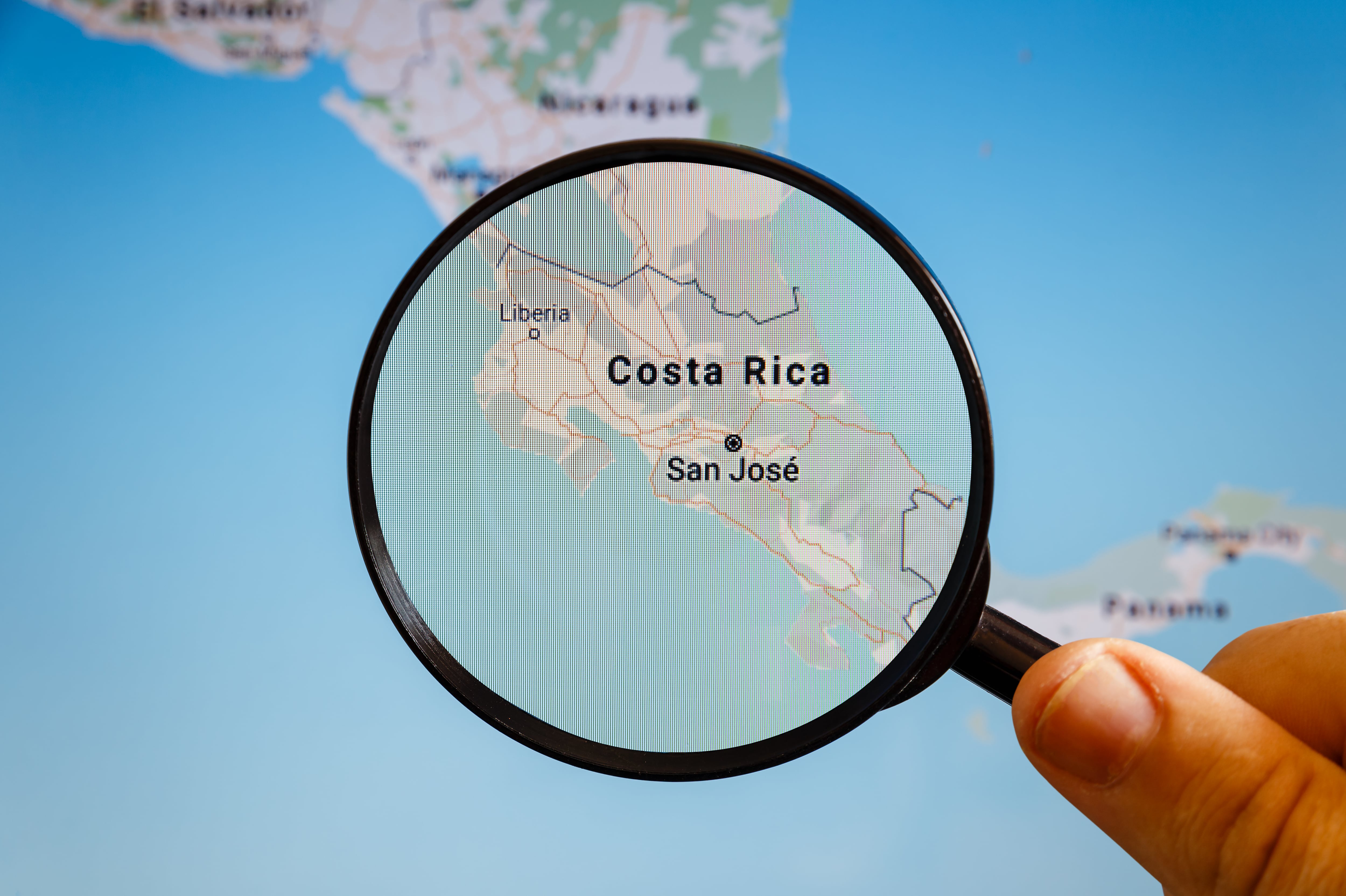 Mano sujeta lupa sobre mapa de Costa Rica