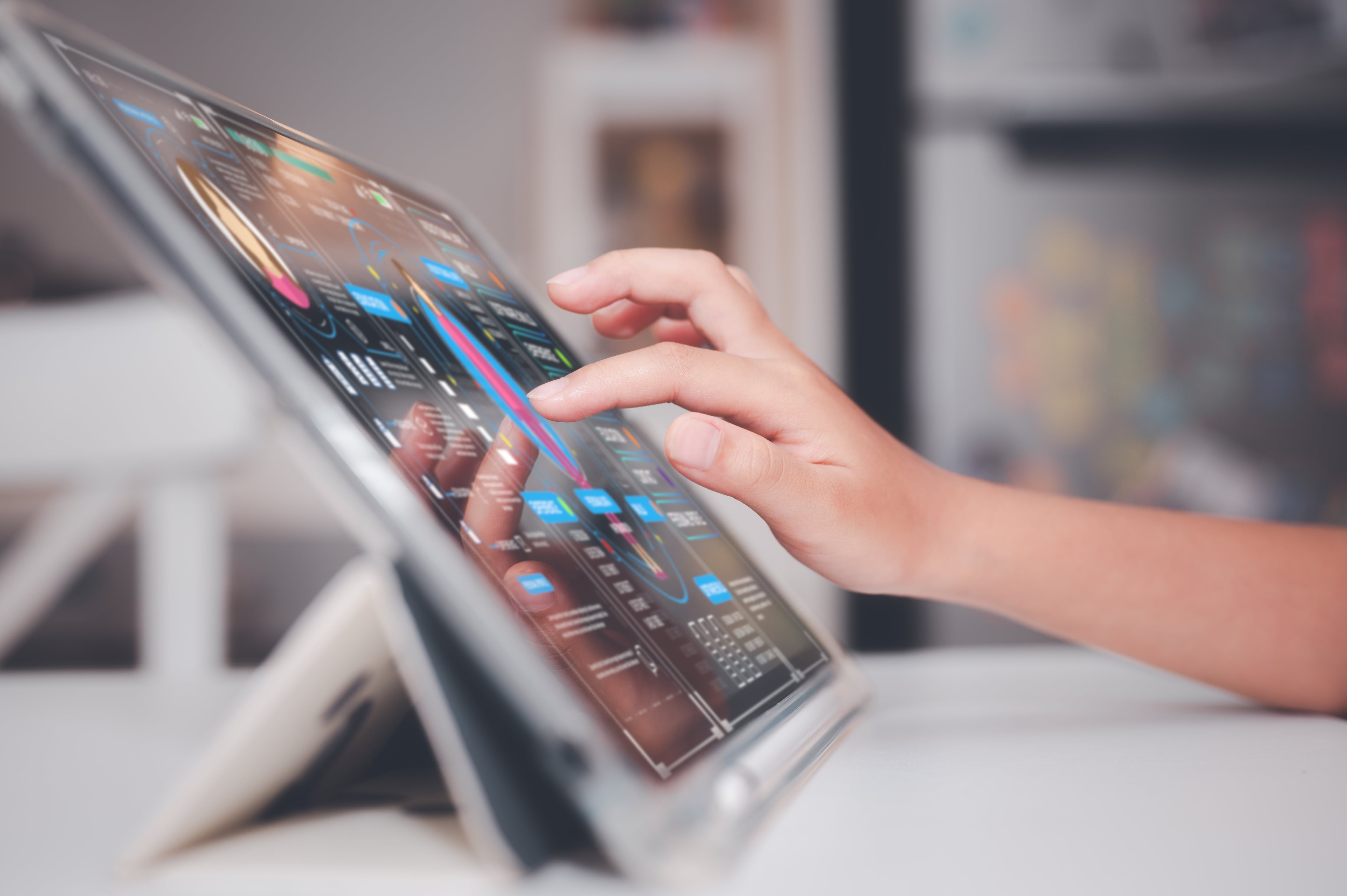 Primer plano de mano de menor de edad usando una tablet, tableta electrónica, sobre una mesa