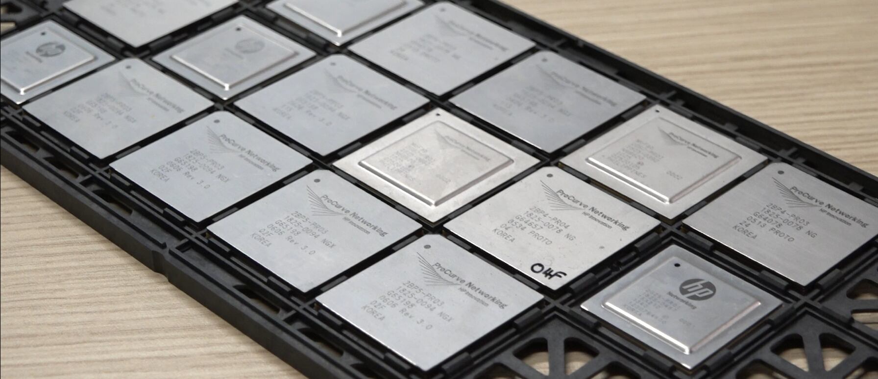 Microchips metálicos de Hewlett Packard Enterprise alineados sobre una bandeja negra en laboratorio de investigación y desarrollo en Costa Rica, donde se desarrollaron 40 nuevas patentes tecnológicas.