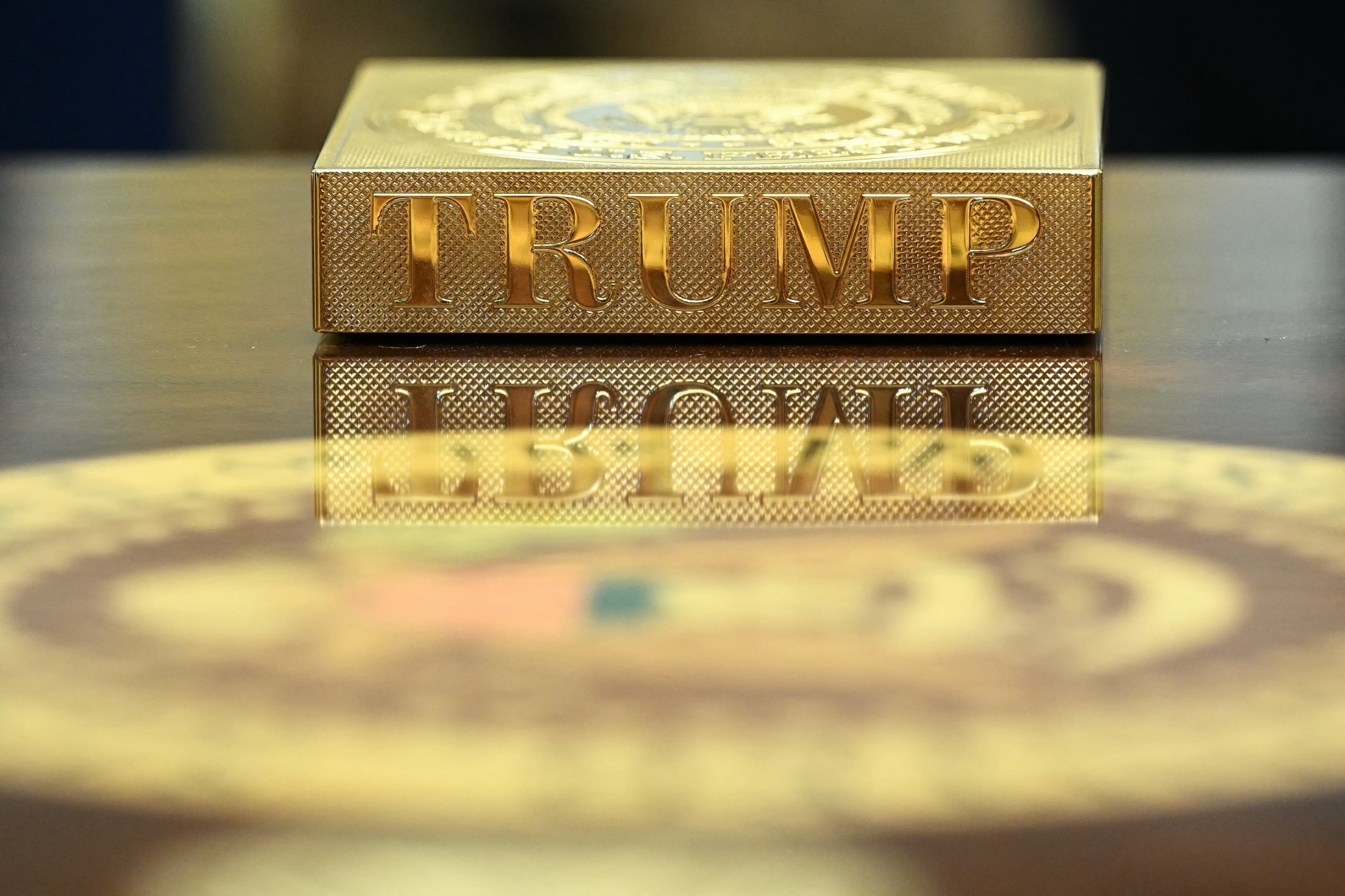(FILES) A gold coaster reading "TRUMP" sits on the table in front of US President Donald Trump as he meets with Irish Prime Minister Micheal Martin in the Oval Office of the White House in Washington, DC, on March 12, 2025. Donald Trump promised a new "Golden Age" for America. In the Oval Office, at least, he has lived up to his promise with a blingy makeov