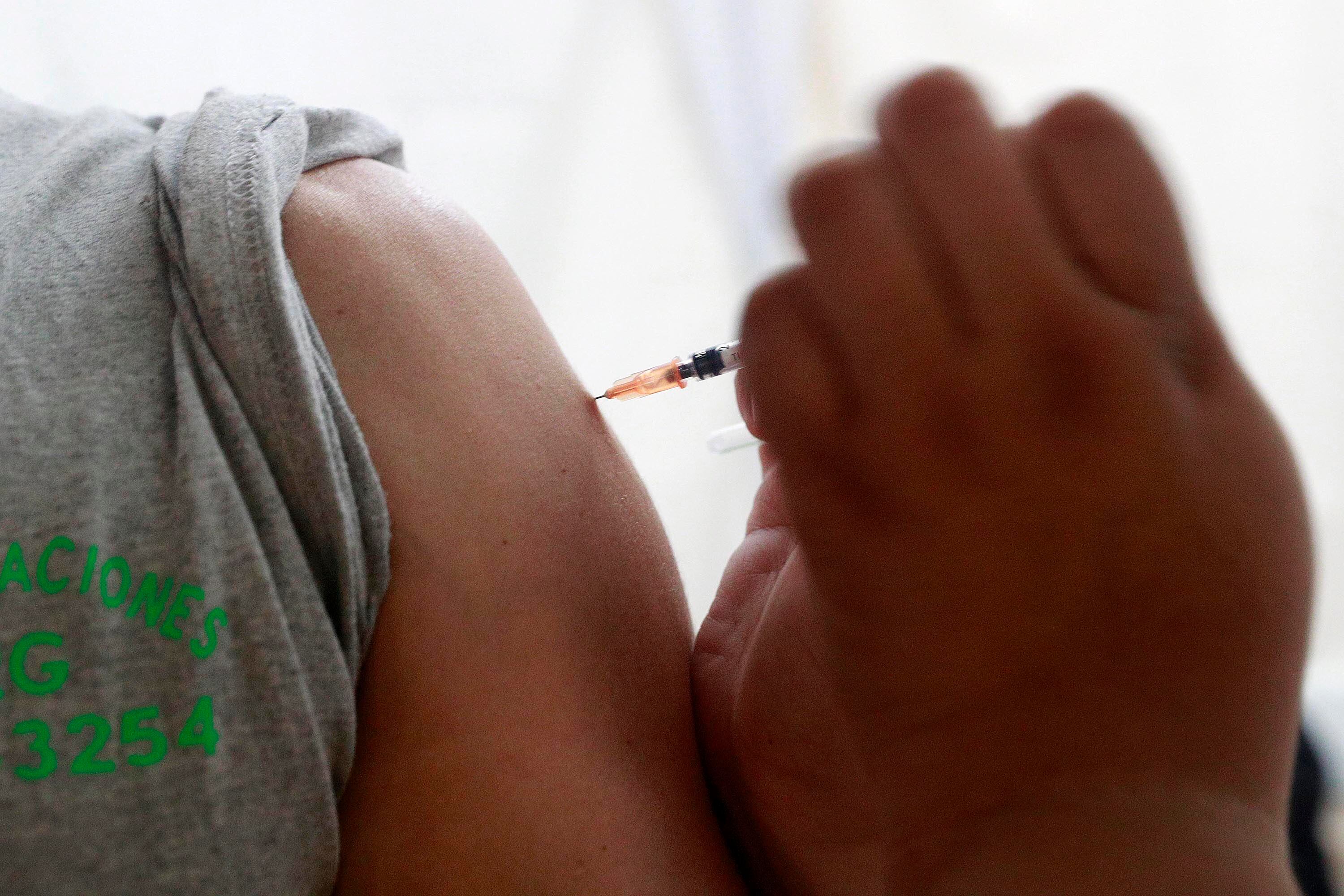 Un brazo recibiendo una vacuna. No se ven las caras de las personas.