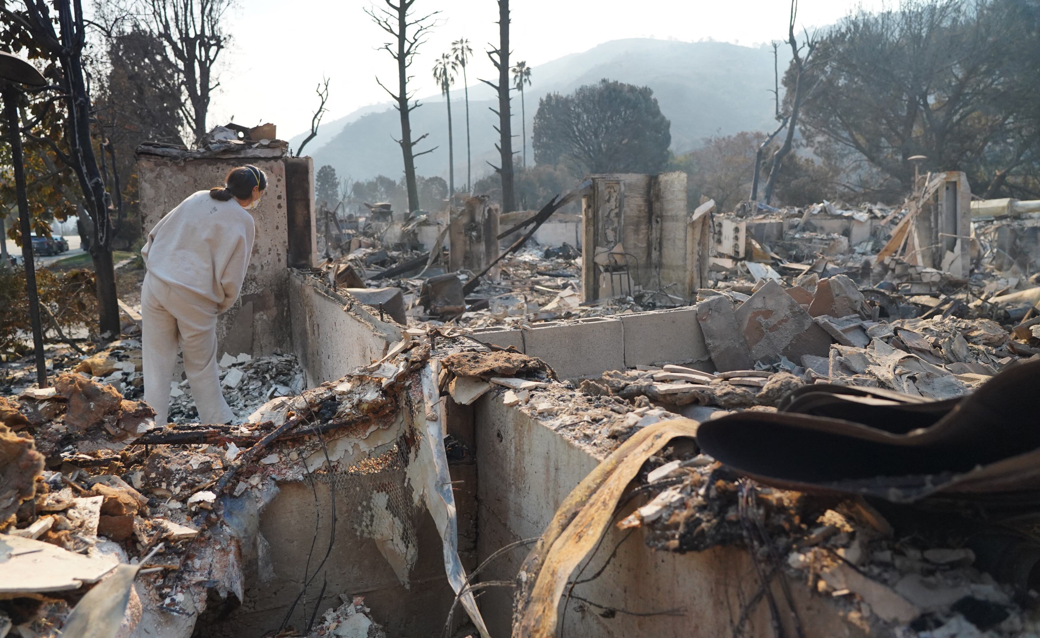 Nicole Perri busca sus pertenencias entre las ruinas de su casa destruida por el incendio de Palisades en el vecindario de Pacific Palisades en Los Ángeles, California