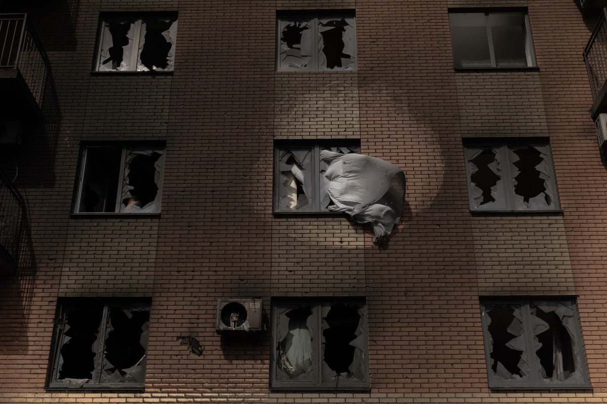 Una cortina se agita desde una ventana rota de un edificio residencial dañado, tras ataques rusos con drones y misiles en Kyiv el 14 de mayo de 2026, en medio de la invasión rusa de Ucrania.