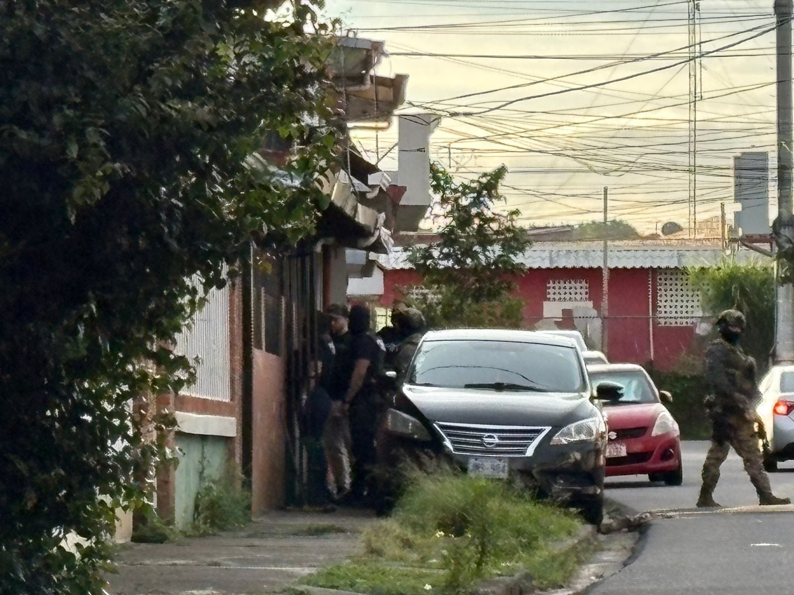 Una calle en un barrio residencial. Automóviles. Agentes del OIJ.