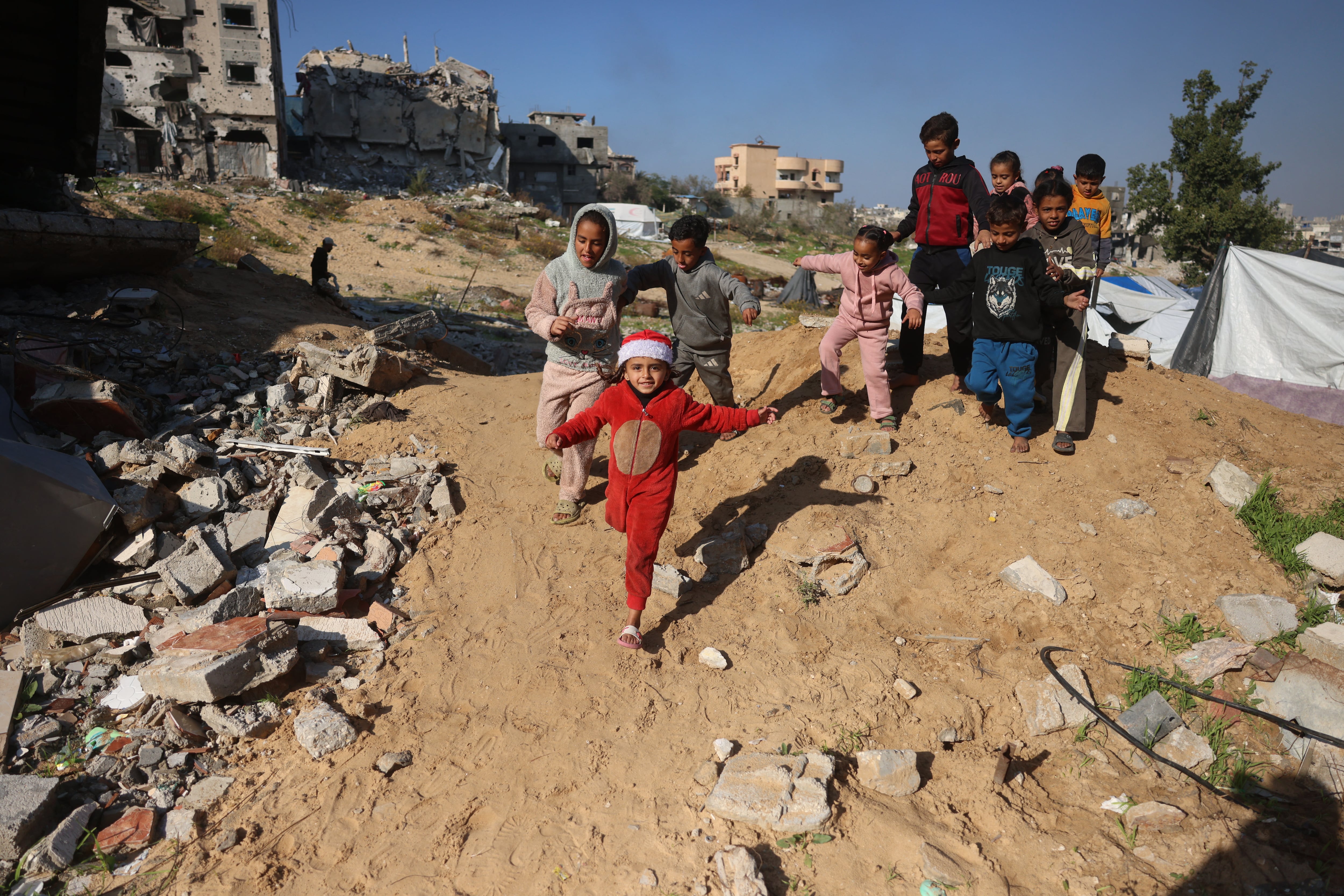 Niños palestinos juegan junto a los escombros de los edificios destruidos en el campo de refugiados de Jabalia, en el norte de la Franja de Gaza, el 24 de diciembre de 2025.