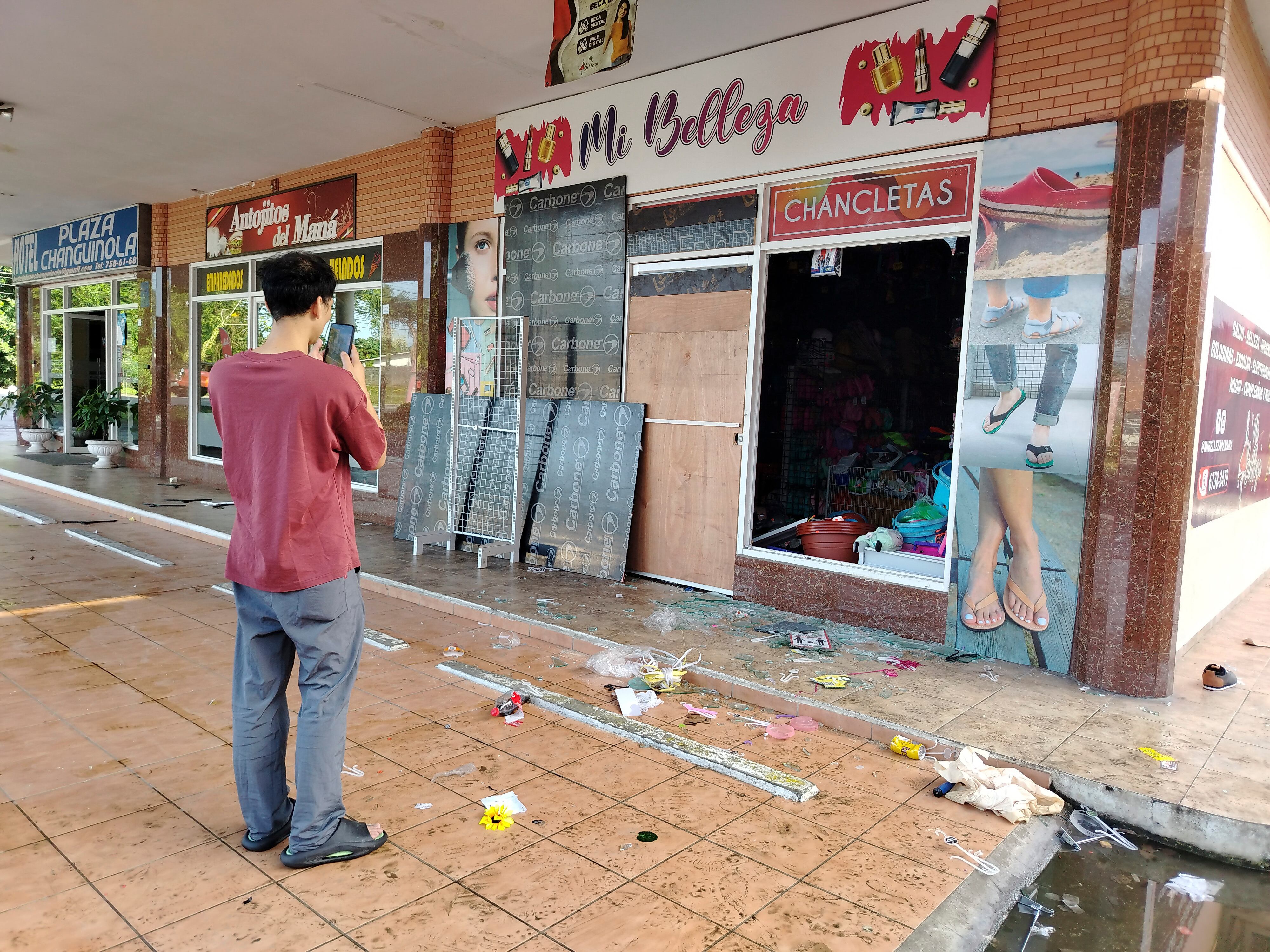 A man takes photographs of damages in a store in the city of Changuinola, Bocas del Toro, on June 20, 2025, after groups of vandals stormed the local airport, looted rental vehicles and various office items, and destroyed commercial properties, according to a police statement. Panama's President Jose Raul Mulino announced he will take "constitutional measures" to curb the ongoing wave of protests and road blockades that have affected the Caribbean province of Bocas del Toro for over a month. (Photo by DANIEL SANTOS / AFP)