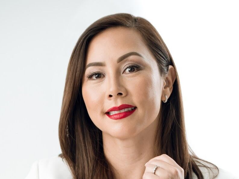 Retrato de Yin Leng Hong Monteverde, nueva presidenta del Conassif, con fondo blanco, vistiendo de blanco y con labios rojos.