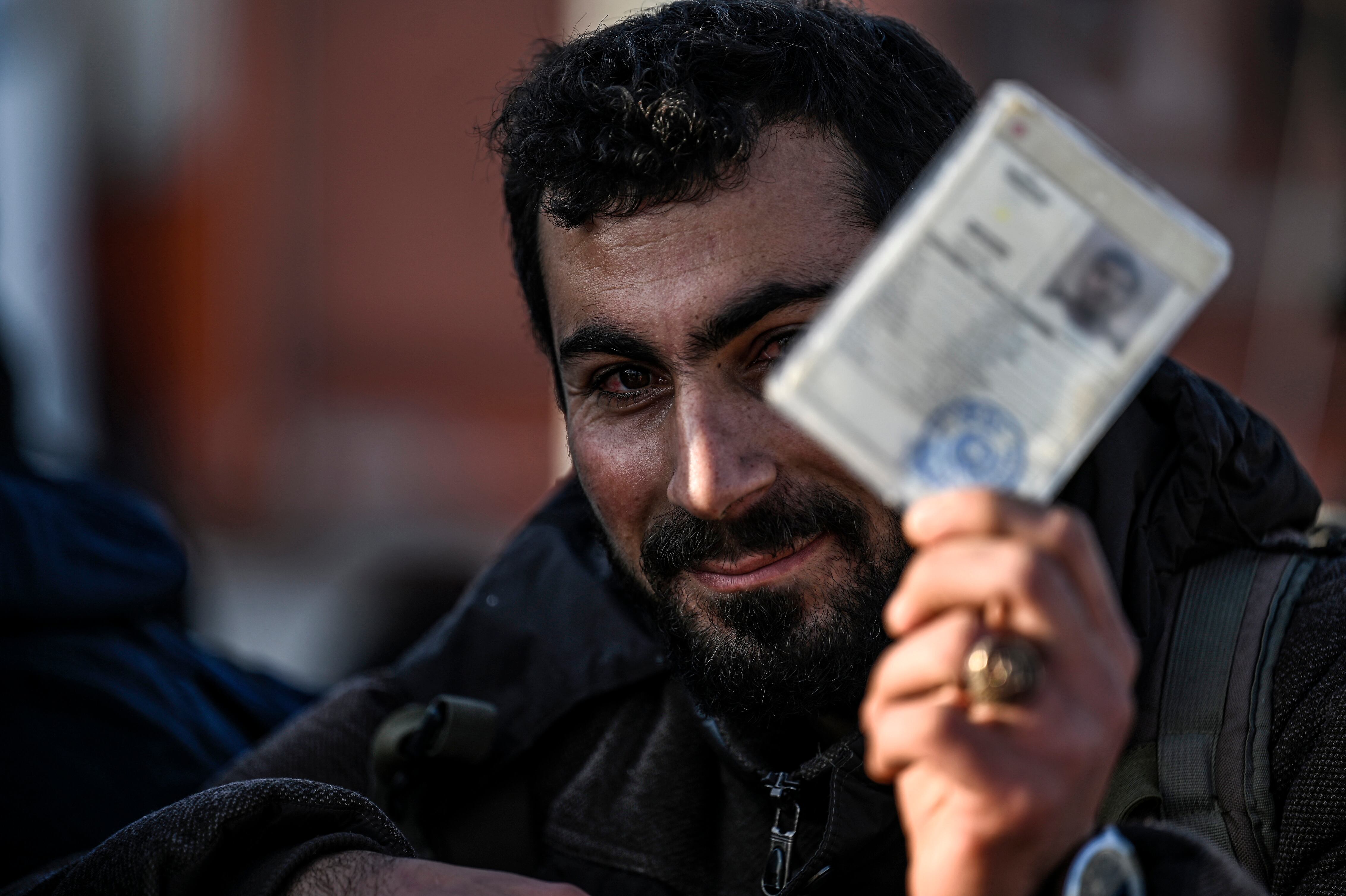 Un hombre sirio que vive en Turquía sostiene su documento de identidad temporal turco mientras hace fila en la puerta fronteriza de Cilvegozu, en el distrito de Reyhanli, Hatay, el 9 de diciembre de 2024, esperando ingresar a Siria tras la caída de Bashar al Asad.